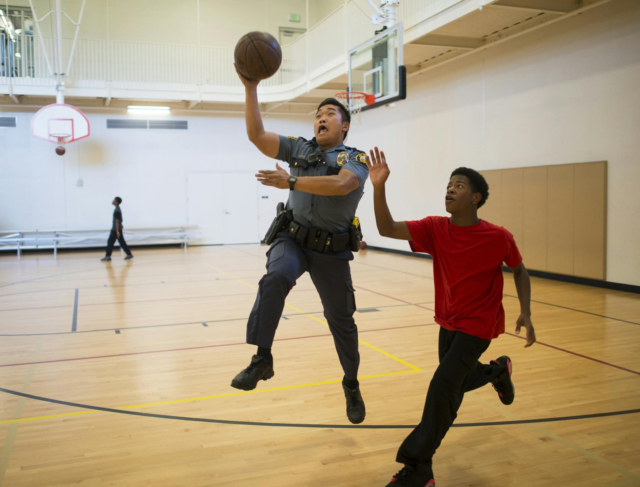 Officer Pheng Xiong played basketball with Ronnie Kemp, 15, at the Arlington Hills Community Center Friday. Xiong stops in at the center every day on his shift to connect with the kids.