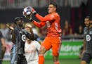 Minnesota United goalkeeper Vito Mannone (1) grabs a ball in front of Ike Opara, left, during the second half of an MLS soccer match against Atlanta U