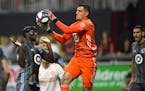 Minnesota United goalkeeper Vito Mannone (1) grabs a ball in front of Ike Opara, left, during the second half of an MLS soccer match against Atlanta U