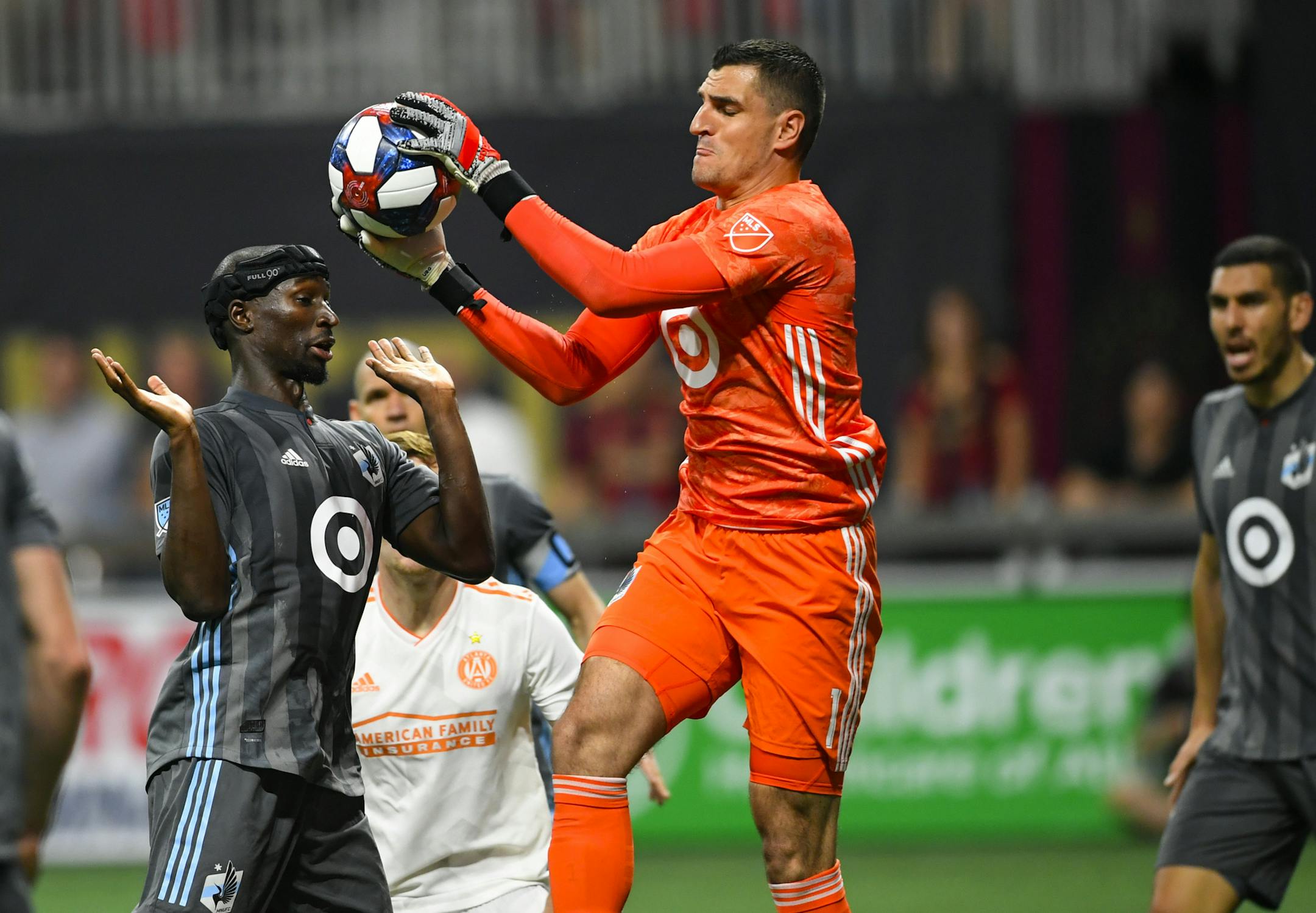 Minnesota United goalkeeper Vito Mannone (1) grabs a ball in front of Ike Opara, left, during the second half of an MLS soccer match against Atlanta United, Wednesday, May 29, 2019, in Atlanta. Atlanta United won 3-0. (AP Photo/John Amis)