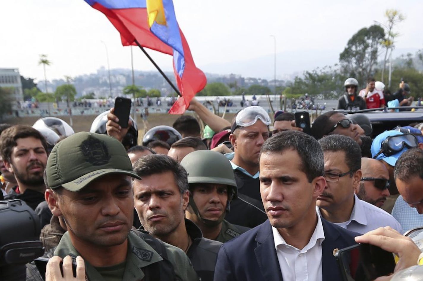 ADDS IDENTIFICATION OF SOLDIER - Venezuela's opposition leader and self-proclaimed president Juan Guaidó, center right, flanked by activist Leopoldo López, center left, stands with National Guard Lieutenant Colonel Ilich Sanchez, who is helping to lead a military uprising, as they talk to the press and supporters outside La Carlota air base in Caracas, Venezuela, Tuesday, April 30, 2019. Guaidó took to the streets with Lopez and a small contingent of heavily armed troops early Tuesday in a bold