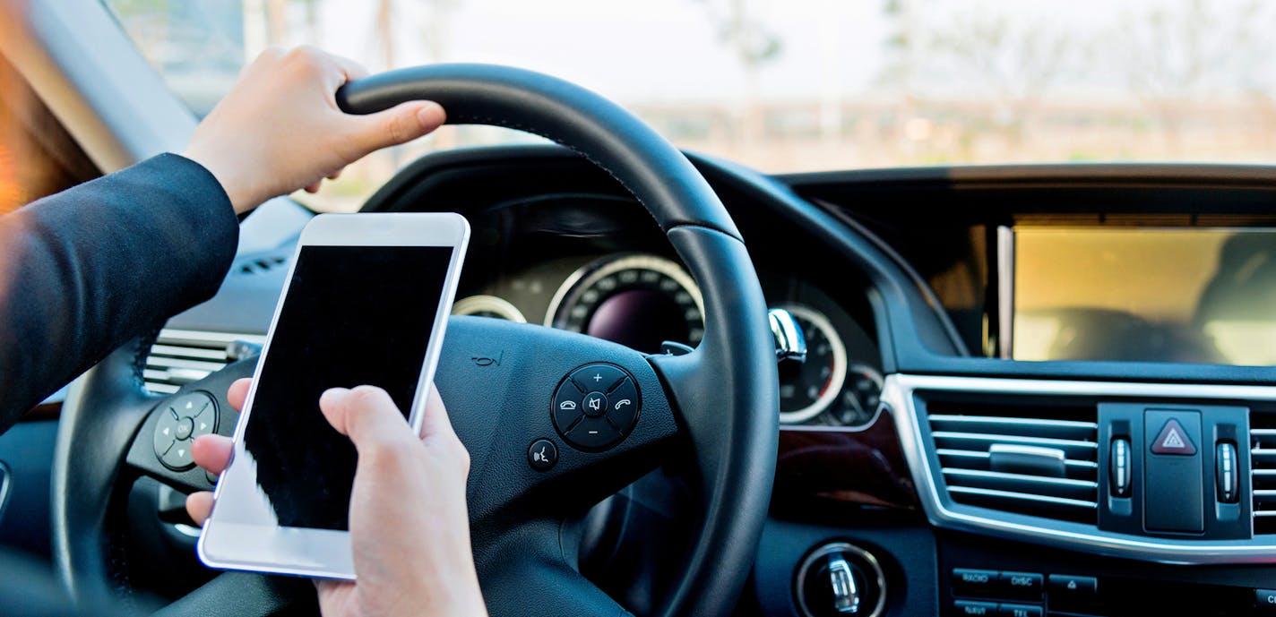 Female driver texting on mobile phone while driving.