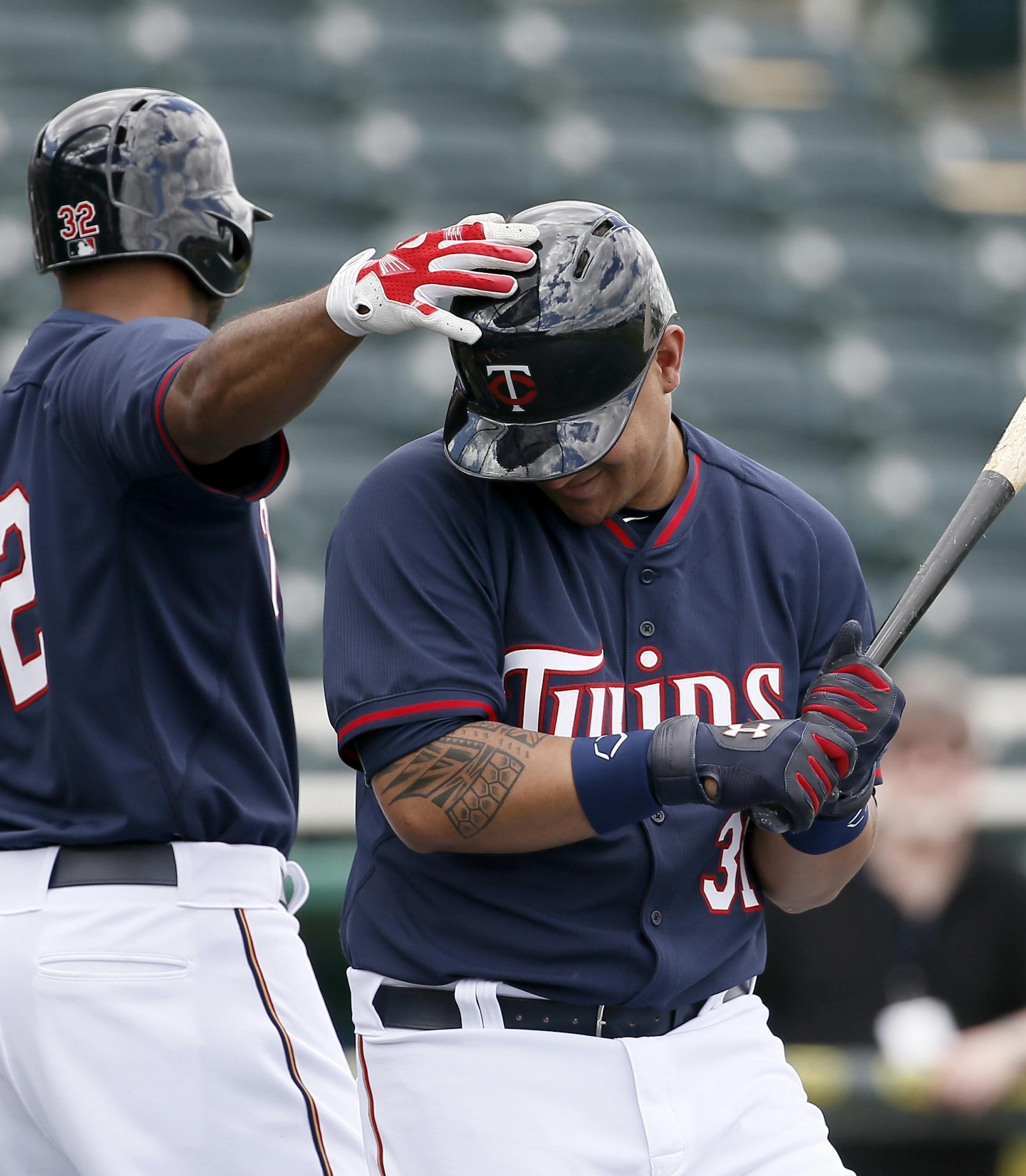 Minnesota Twins' Aaron Hicks (32) taps, Oswaldo Arcia, on the helmet as the two take batting practice at baseball spring training in Fort Myers, Fla., Tuesday March 3, 2015. (AP Photo/Tony Gutierrez)
