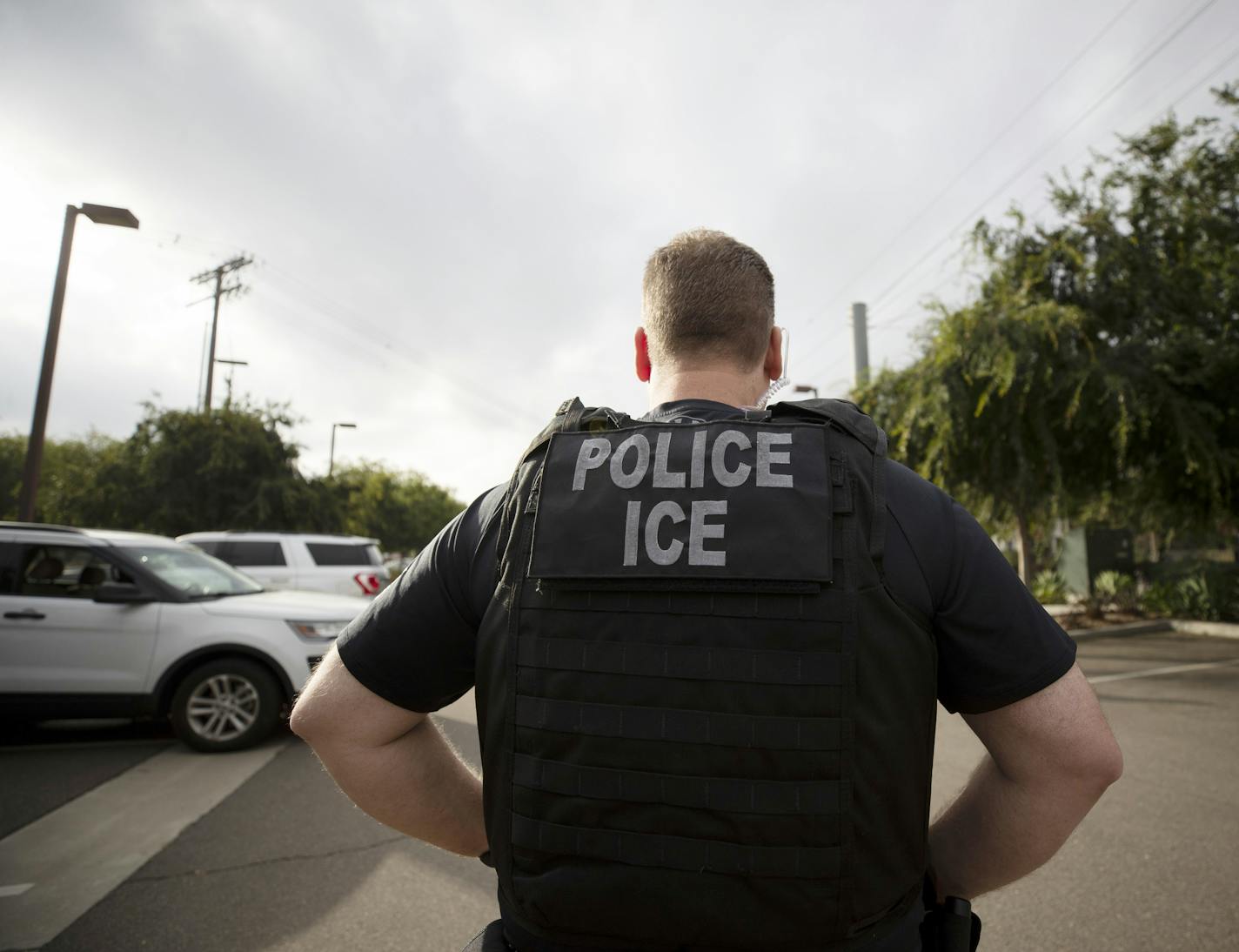 FILE - In this July 8, 2019, file photo, a U.S. Immigration and Customs Enforcement (ICE) officer looks on during an operation in Escondido, Calif. Pressure is mounting on the Trump administration to release people from immigration detention facilities where at least one detainee has already tested positive for COVID-19. (AP Photo/Gregory Bull, File)