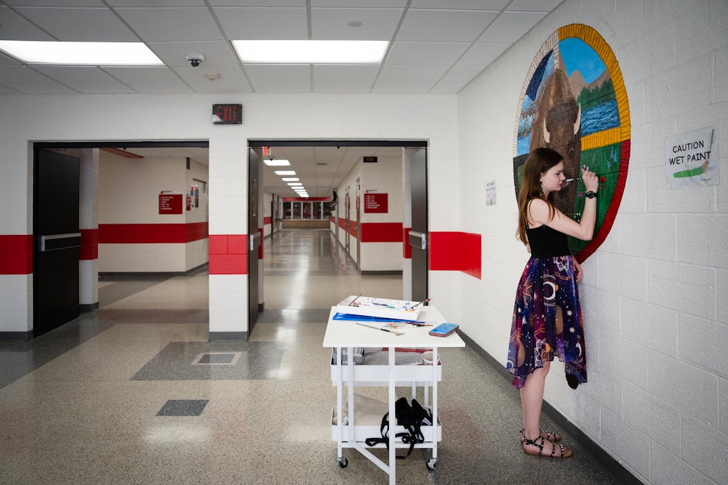 Lexi Sanburg works on the mural she’s painting in a hallway of Centennial High School on Thursday.