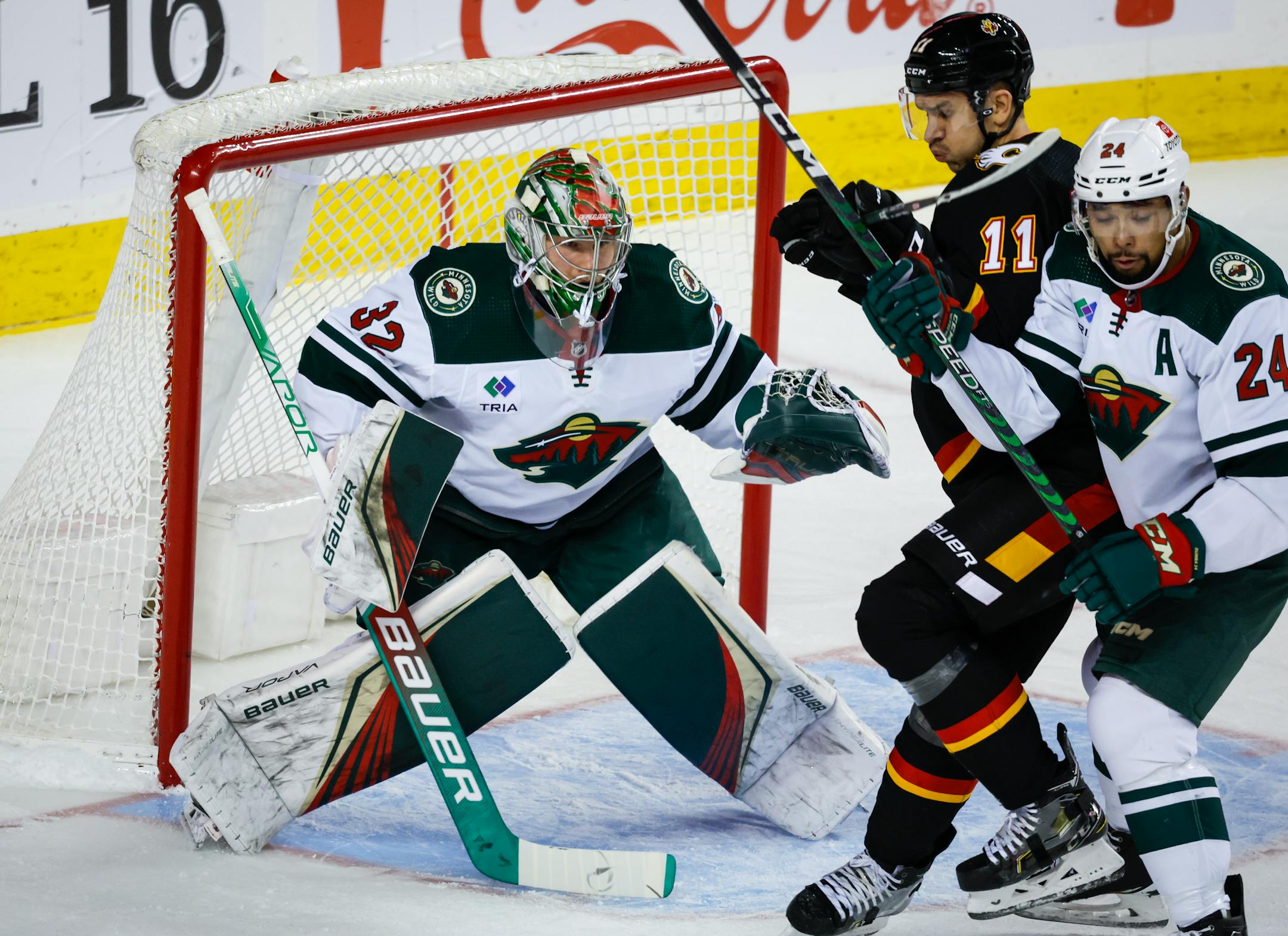 Wild defenseman Matt Dumba, right, checks Calgary forward Mikael Backlund in front of goalie Filip Gustavsson during the first period