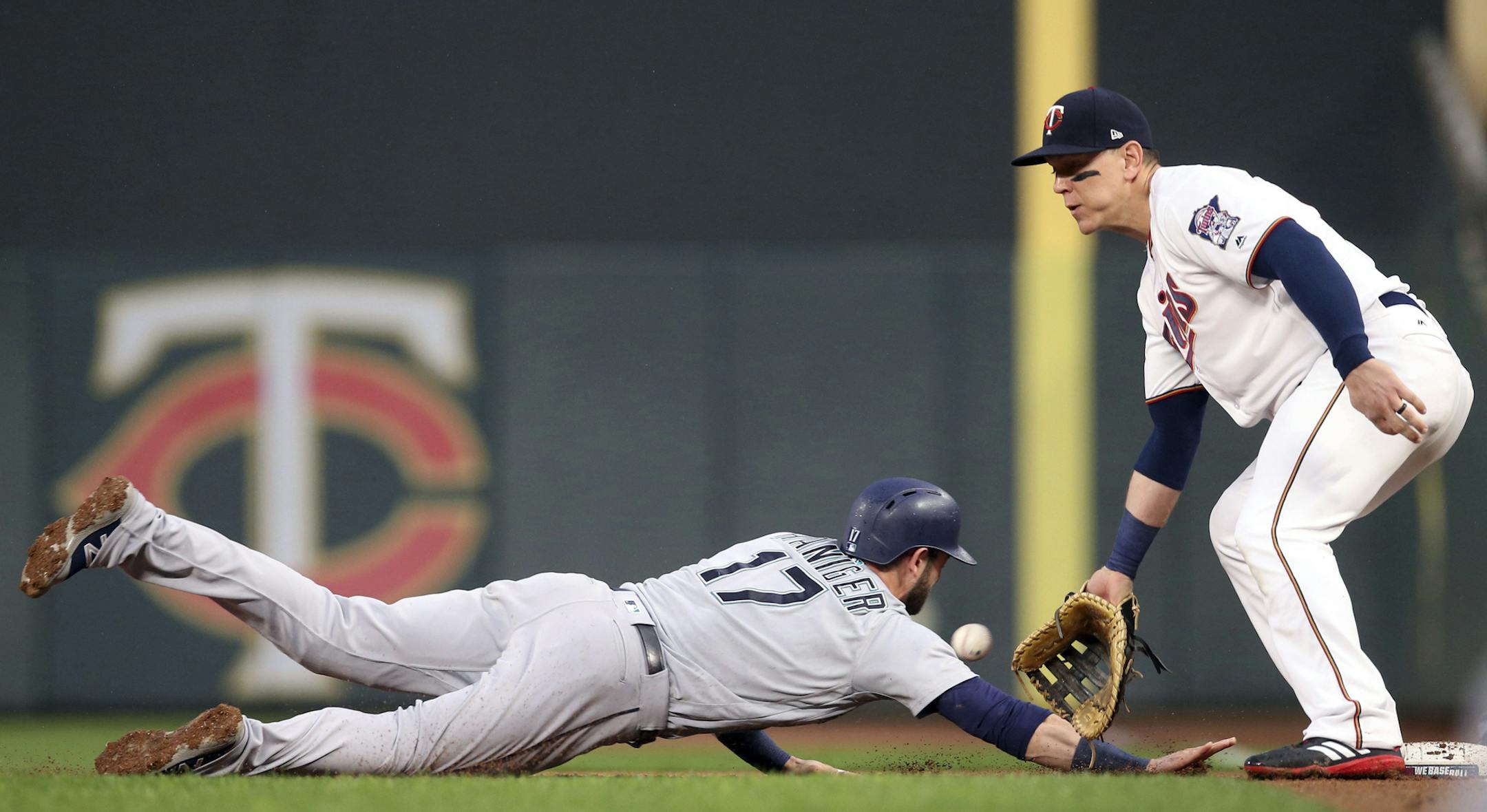 Seattle Mariners' Mitch Haniger, left, beats the throw to Minnesota Twins first baseman Logan Morrison in a pickoff attempt in the first inning of a makeup baseball game Monday, May 14, 2018, in Minneapolis. (AP Photo/Jim Mone)
