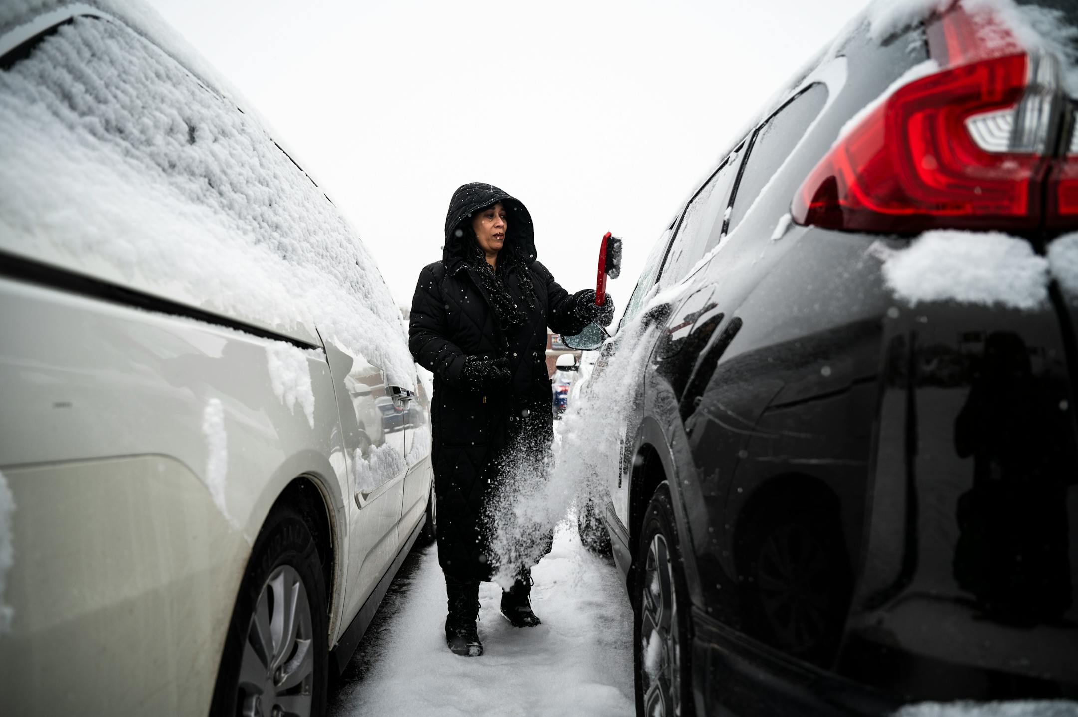 Tara Parrish, of north Minneapolis, brushes off her SUV after grocery shopping Tuesday, outside Hy-Vee in Robbinsdale.