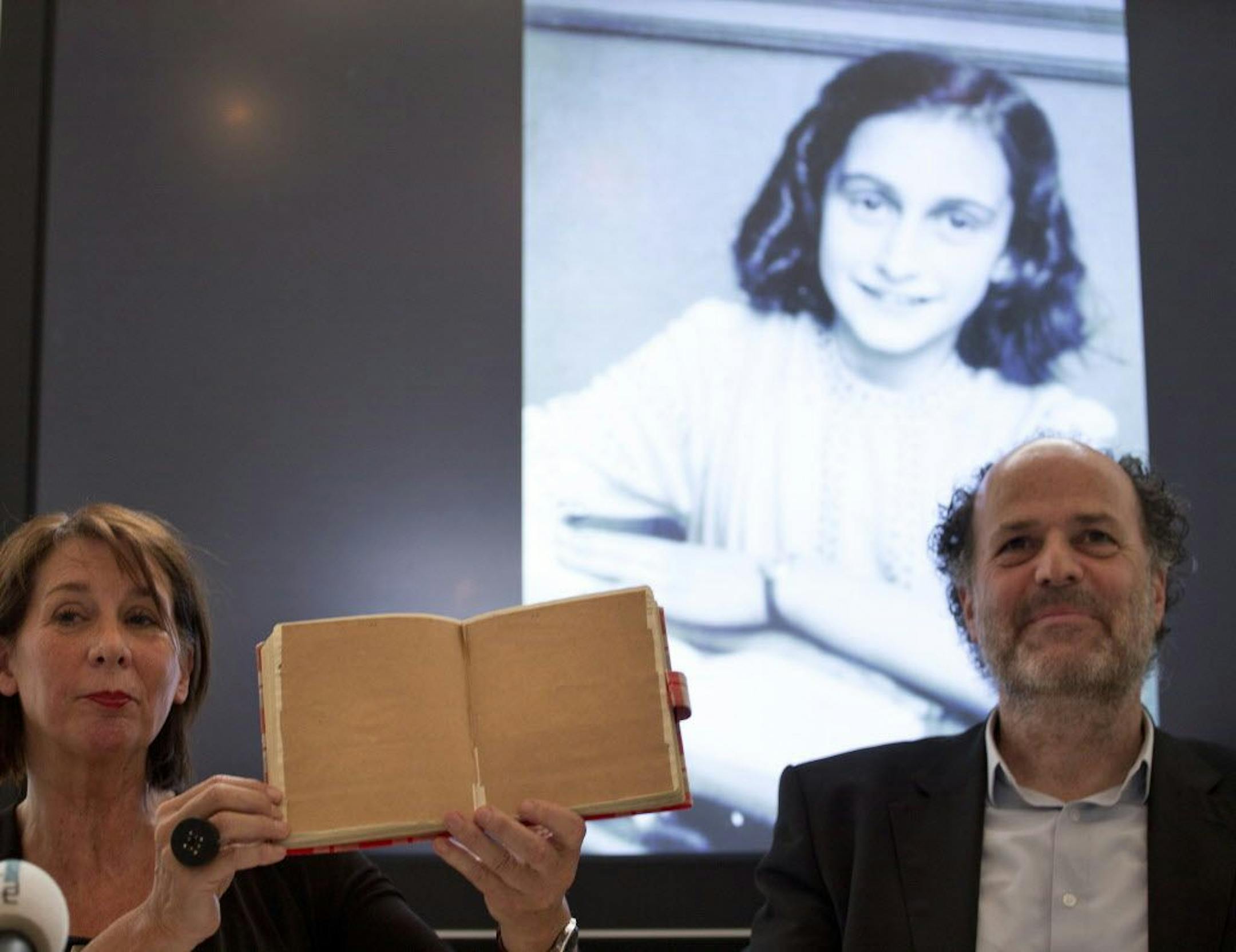Teresien da Silva, left, and Ronald Leopold of the Anne Frank Foundation show a facsimile of Anne Frank's diary with two pages taped off during a press conference at the foundation's office in Amsterdam, Netherlands, Tuesday, May 15, 2018. Researchers have used digital photo editing techniques to uncover the text on two pages from Anne Frank's world famous diary that the teenage Jewish diarist had covered with brown masking paper, revealing risque jokes and an explanation of sex and prostitution