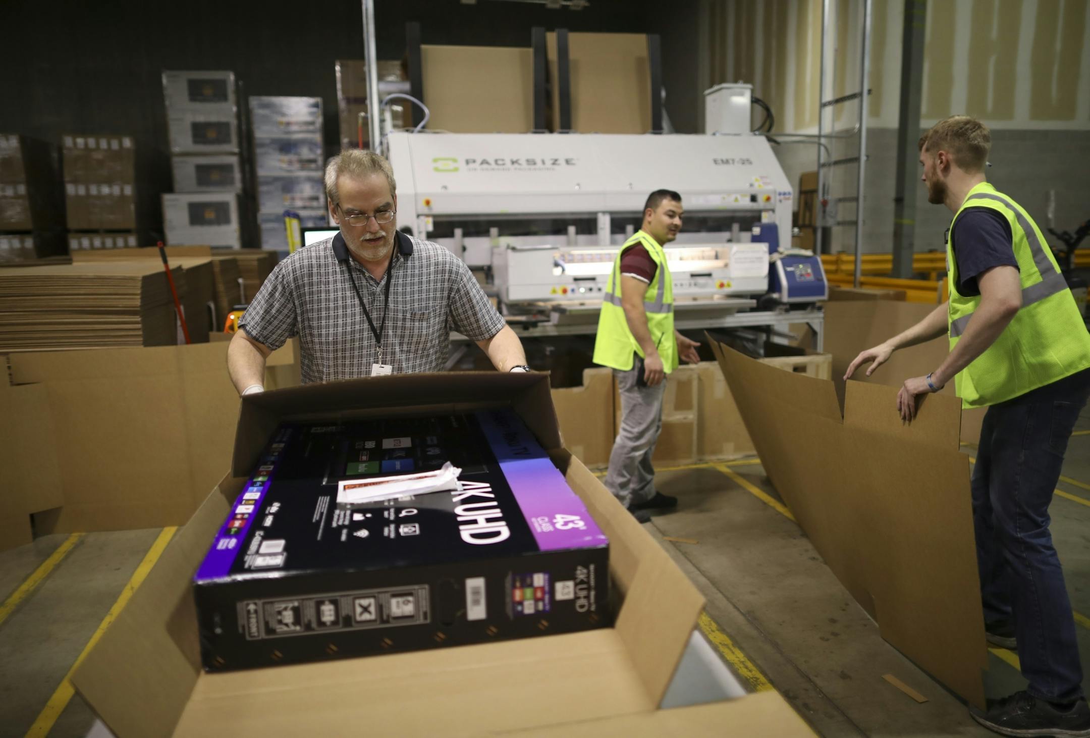 Mark Fleisher, boxed up a flat screen televison for shipping Monday afternoon after making a custom sized box for it with the Packsize on-demand box fabricating machine at right. He was working in the Best Buy distribution center in Bloomington.