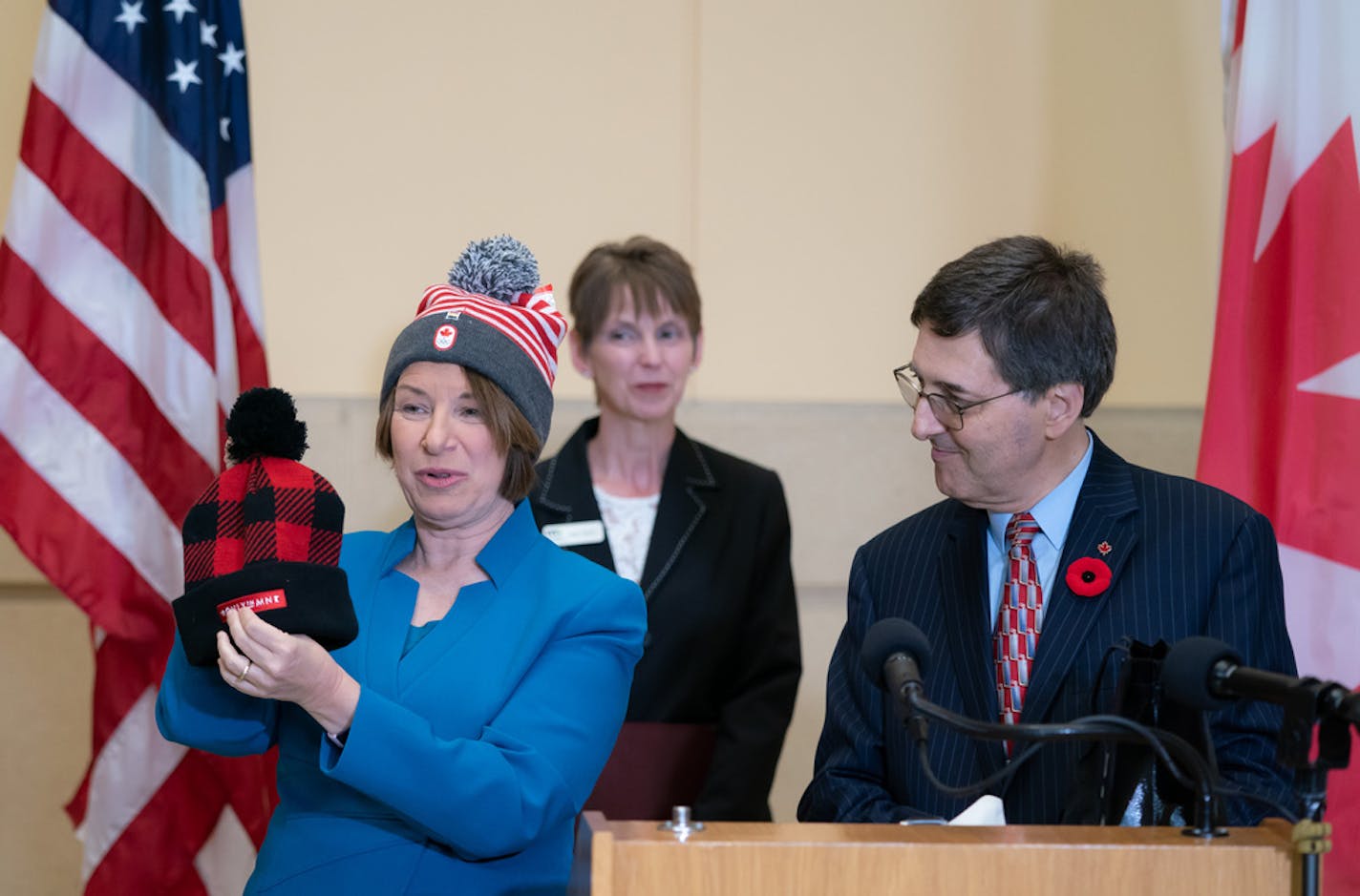 Wearing a hat given to her by Ariel Delouya, right, Consul General of the Consulate General of Canada in Minneapolis, U.S. Senator Amy Klobuchar showed off the hat she presented to Delouya. They held a conference celebrating the reopening of the U.S.-Canada border for tourism, Monday, Nov. 8, 2021, at RiverCentre, St. Paul, Minn.