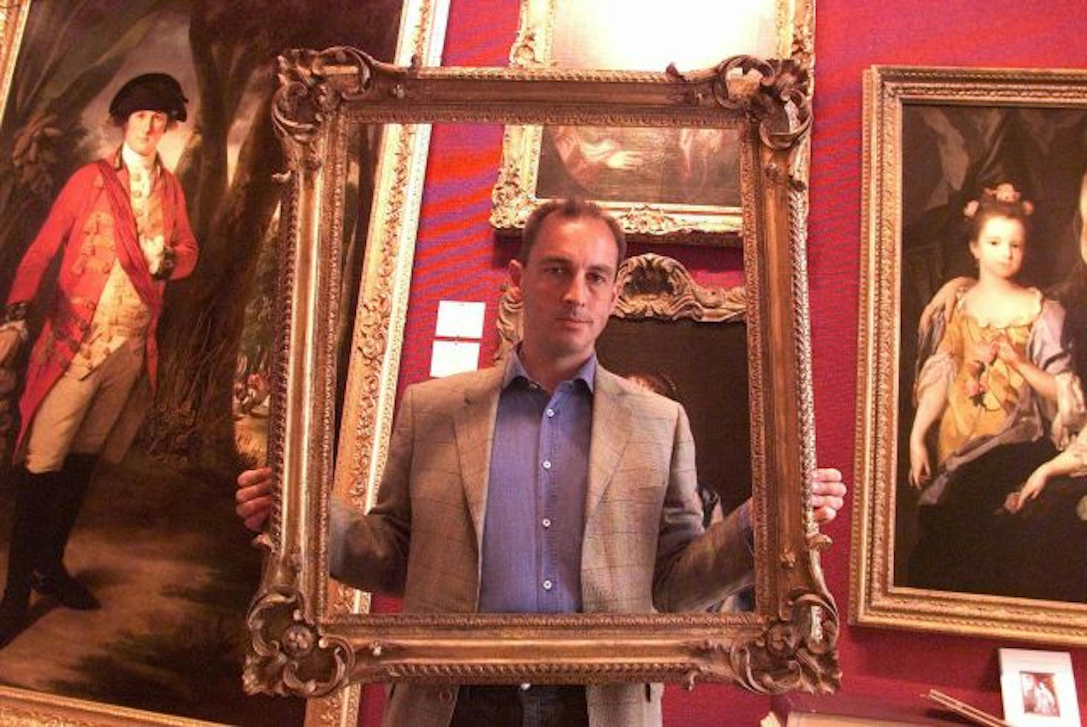 Holding an empty picture frame, Phillip Mould stands in his gallery in London, September 2, 1999. Behind him are paintings "Maj. Gen Horton Briscoe, The Meritorious Officer" painted by Tilly Kettle in the 17th century and Queen Henrietta Maria painted by the circle of Sir Anthony Van Dyck in the 17th century. In the past 15 years, Mould has rescued from obscurity five Van Dycks, "three or four" Gainsboroughs, a rare painting of King Henry VIII's oldest brother and a portrait by George Romney tha