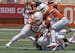 FILE - In this April 24, 2021, file photo, Texas defenders Jake Ehlinger, left, and B.J. Foster, right, tackle Kayvontay Dixon (16) during the first h