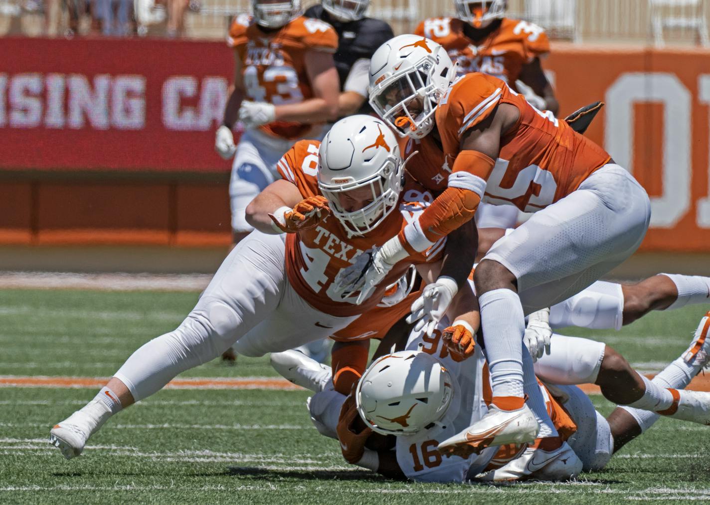 FILE - In this April 24, 2021, file photo, Texas defenders Jake Ehlinger, left, and B.J. Foster, right, tackle Kayvontay Dixon (16) during the first half of the Orange and White spring scrimmage college football game in Austin, Texas. Ehlinger, the younger brother of former Longhorns quarterback Sam Ehlinger, was found dead near campus Thursday, May 6, Austin police said. Officers found the 20-year-old Ehlinger after responding to a call at 12:18 p.m. Police did not detail how they found him but said the death is not considered suspicious. No cause of death was immediately released. (AP Photo/Michael Thomas, File)