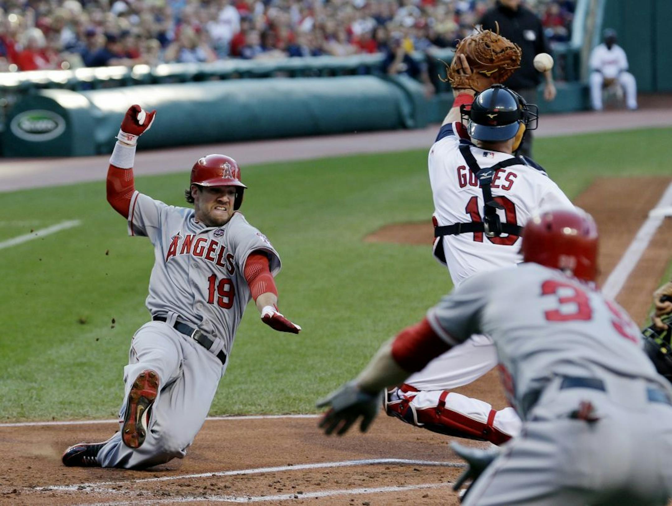 Los Angeles Angels' Collin Cowgill scores as Cleveland Indians' Yan Gomes (10) waits for the ball in the first inning of a baseball game, Friday, Aug. 9, 2013, in Cleveland. J.B. Shuck watches. Shuck and Cowgill scored on a single by Mark Trumbo.