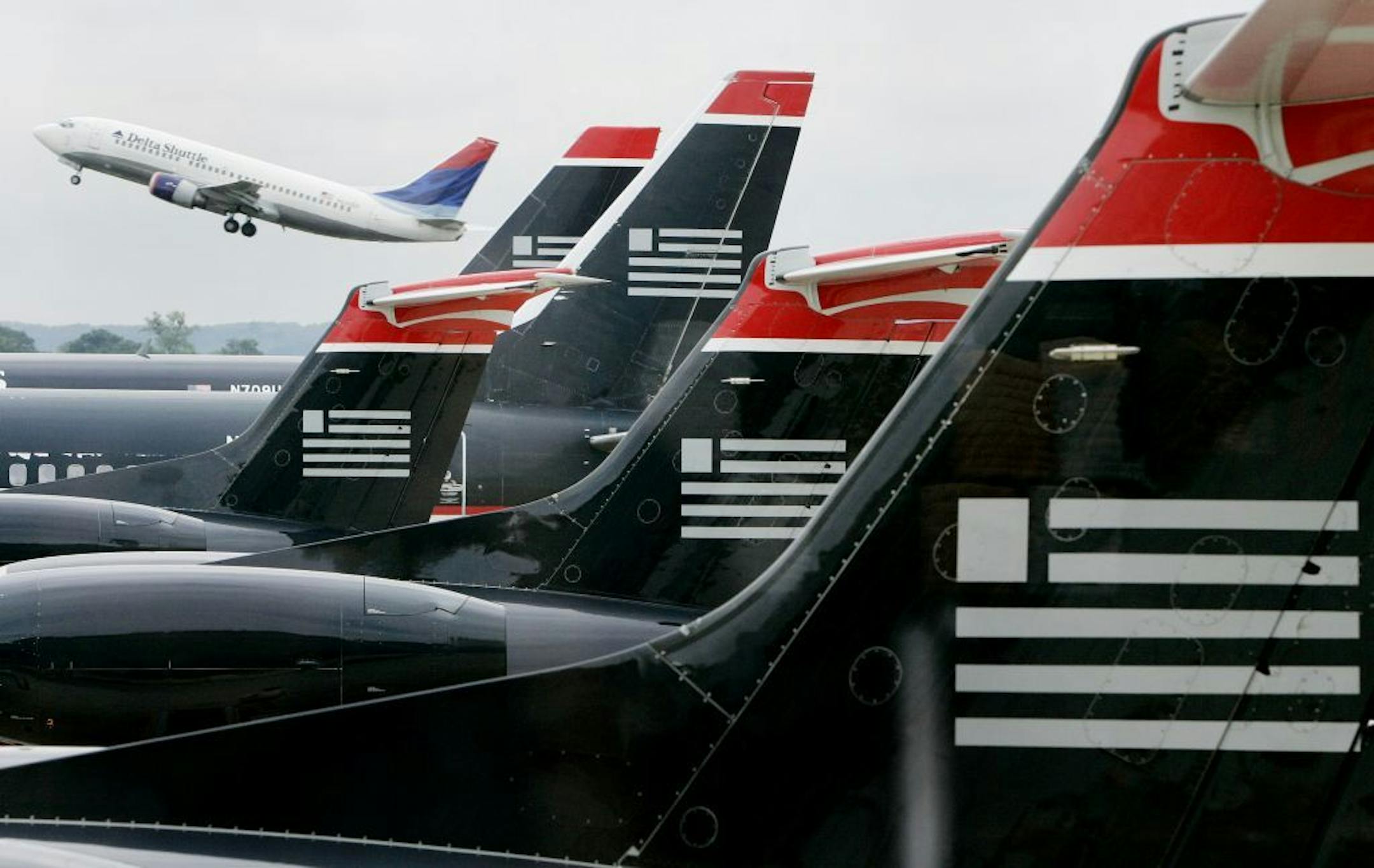 US Airways jets sit in foreground while a Delta aircraft takes off at Reagan National Airport outside Washington, August 13, 2004. US Airways Group Inc. could seek bankruptcy protection by mid-September if it does not get the cost cuts it needs, investment bankers working for the airline's pilot union said in a report. US Airways shares fell more than 9 percent on Friday, after the 26-page report by Glanzer & Co. released this week, essentially confirmed the No. 7 U.S. airline's wary outlook for