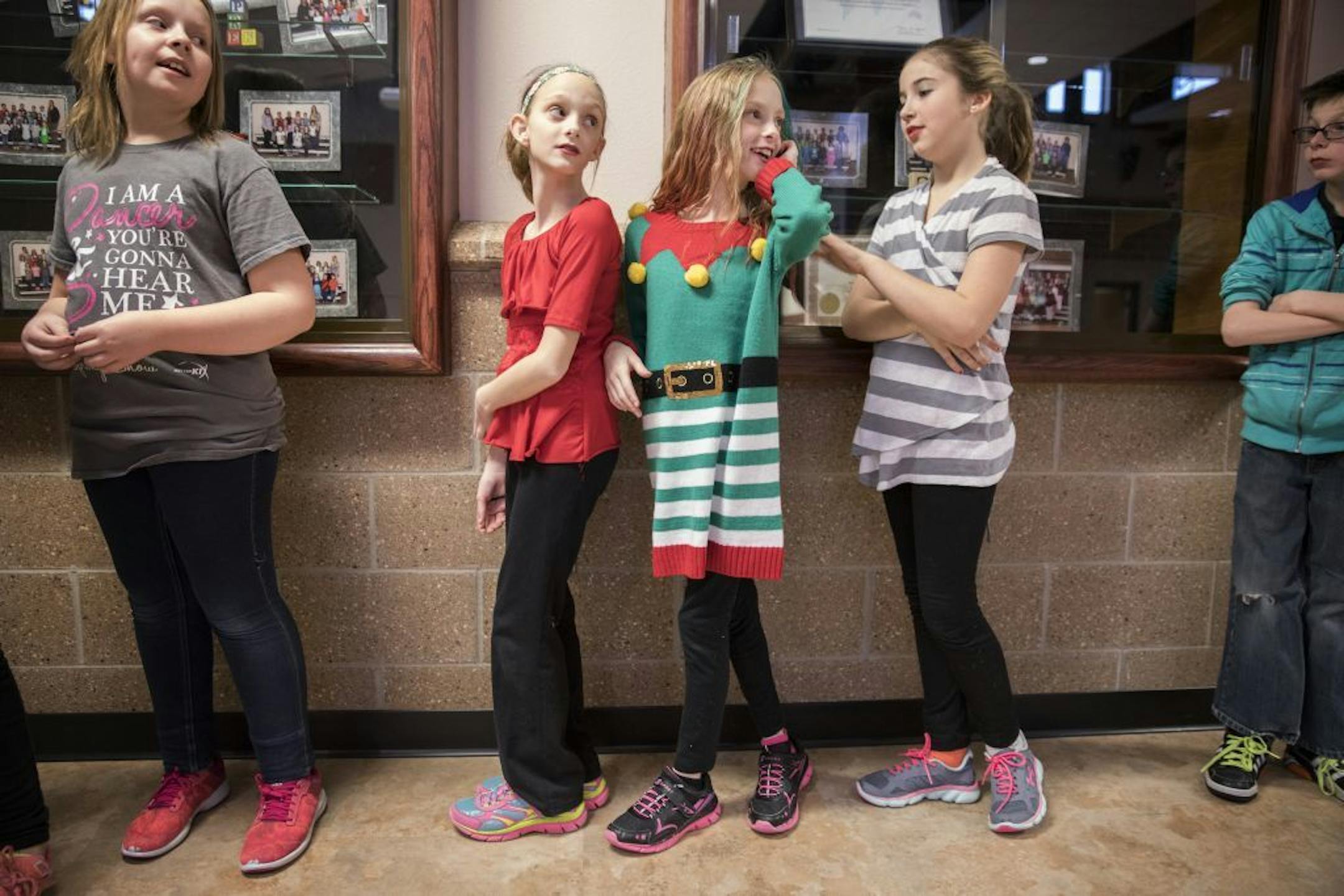 Isabelle Carlsen, in red from left, and her sister Abby wait in line with their friend Jadah Alyea at school.
