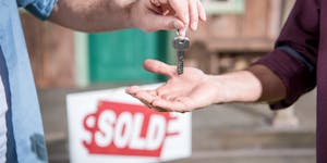 cropped view of man buying new house and taking keys, sold sign behind