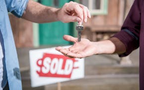 cropped view of man buying new house and taking keys, sold sign behind