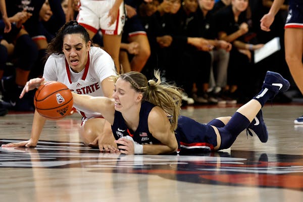 North Carolina State's Mimi Collins dives for a ball with UConn's Paige Bueckers during the 2023 season.