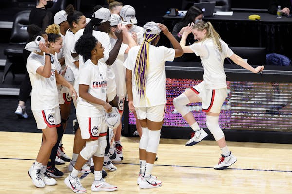 Connecticut's Paige Bueckers, right, dances over to teammates while celebrating an NCAA college basketball game win in the Big East tournament finals 