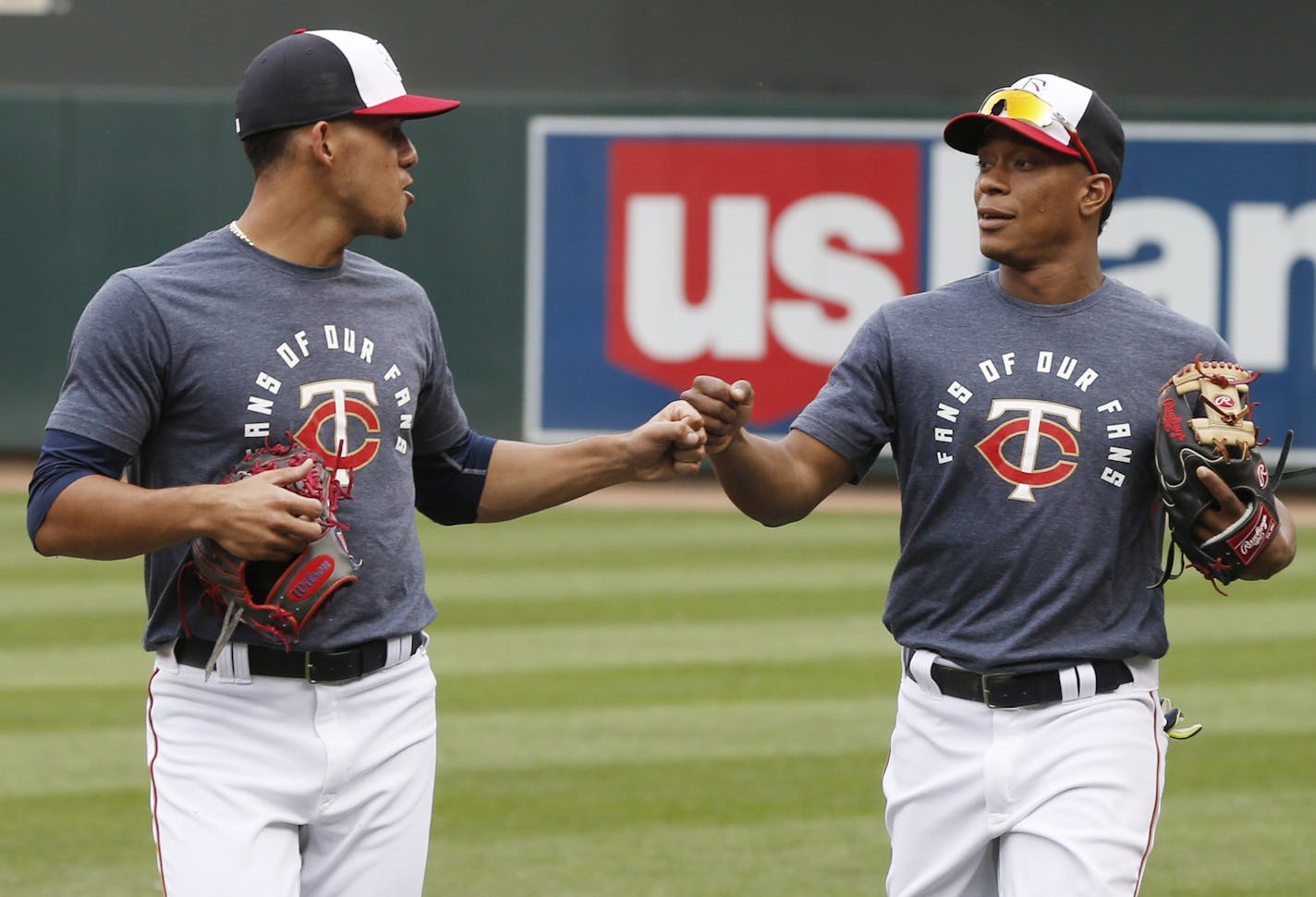 Minnesota Twins pitcher Jose Berrios, left, and infielder Jorge Polanco bump fists after warm-ups for a baseball game against the Cleveland Indians on Friday, Sept. 9, 2016, in Minneapolis where they wore warmup shirts with the phrase "FANS OF OUR FANS" in appreciation of season-ticket holders. (AP Photo/Jim Mone)