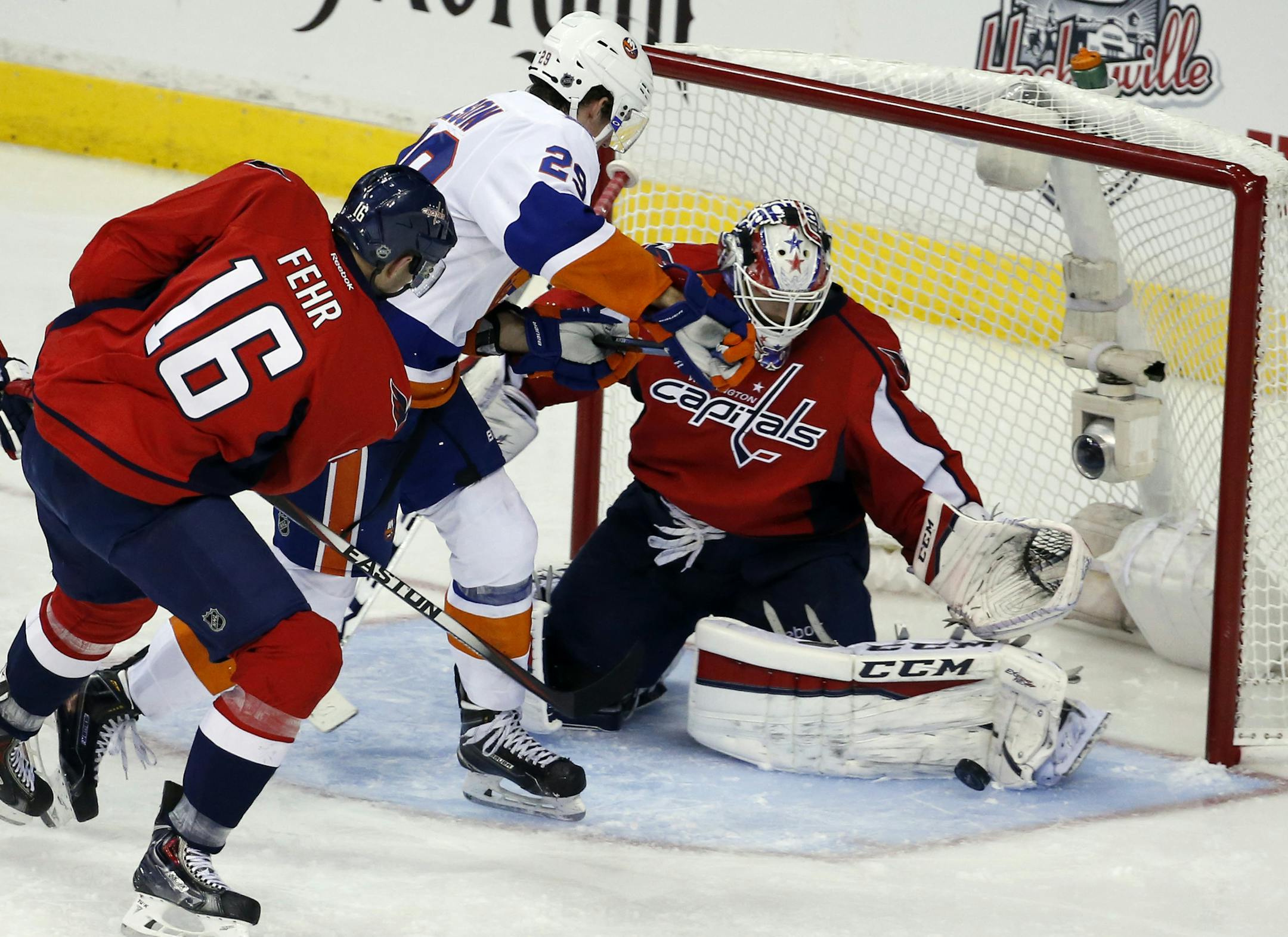 Washington Capitals right wing Eric Fehr (16) defends with goalie Braden Holtby (70) as New York Islanders center Brock Nelson (29) works in front of the net during the third period in the opening game of a first-round NHL hockey playoff series, Wednesday, April 15, 2015, in Washington. The Islanders won 4-1. (AP Photo/Alex Brandon)