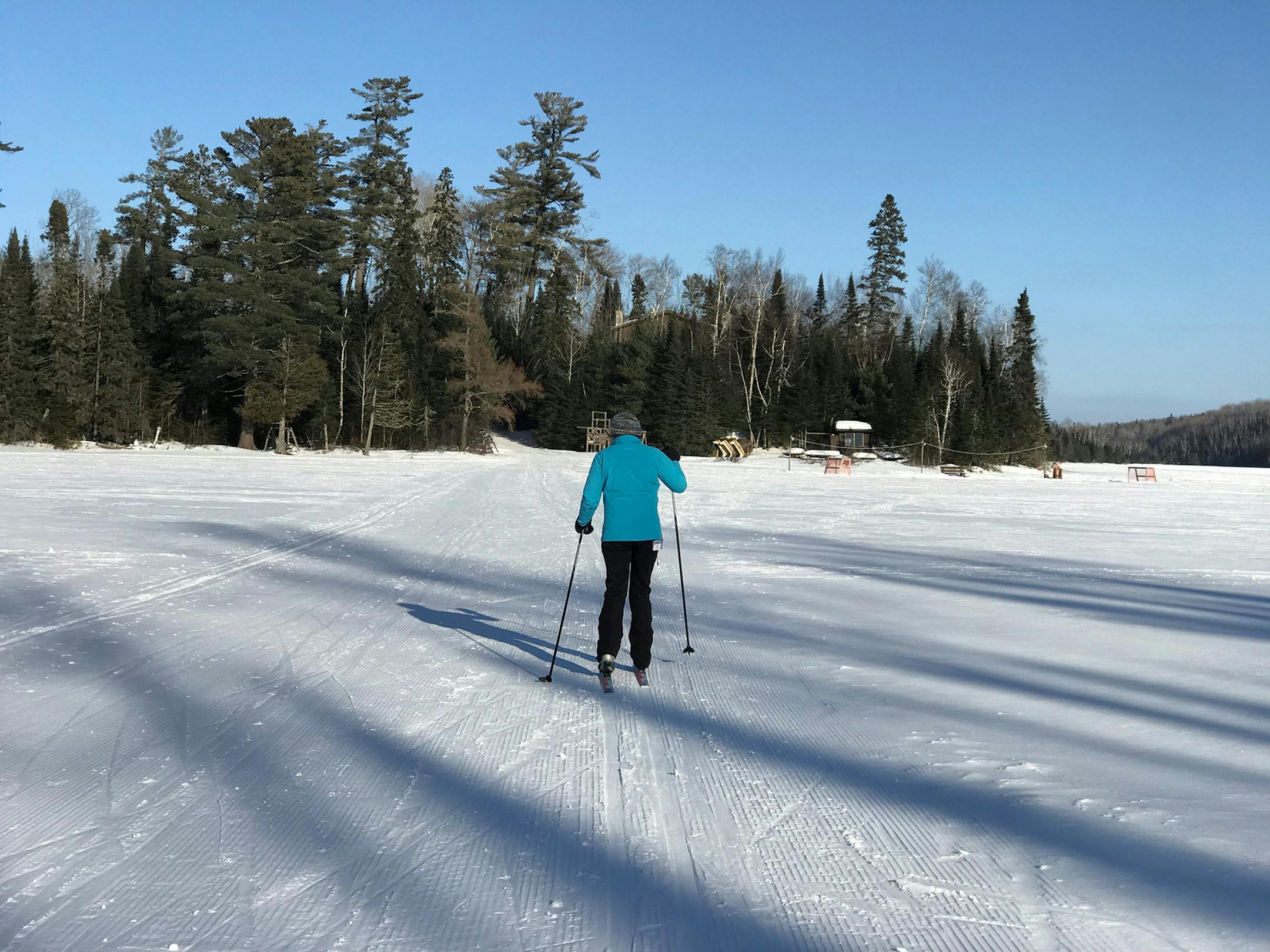 A skier crosses frozen Bearskin Lake toward Bearskin Lodge. A makeshift hockey and ice skating rink, where snow is shoveled from the lake, sits near the main lodge. Photo by Kerri Westenberg/Star Tribune