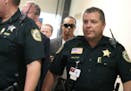 Golfer Tiger Woods, center, makes his way into a North County Courthouse courtroom in Palm Beach Gardens, Fla., Friday Oct. 27, 2017, to plead guilty 