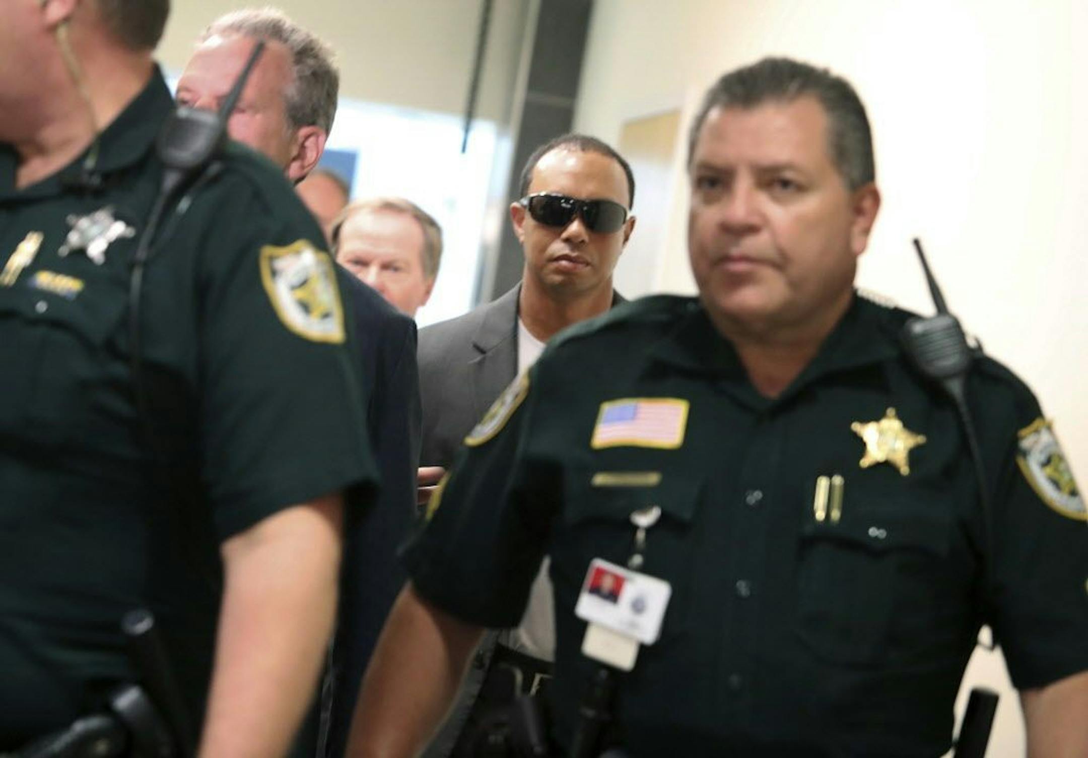 Golfer Tiger Woods, center, makes his way into a North County Courthouse courtroom in Palm Beach Gardens, Fla., Friday Oct. 27, 2017, to plead guilty to a second-degree misdemeanor reckless driving charge.