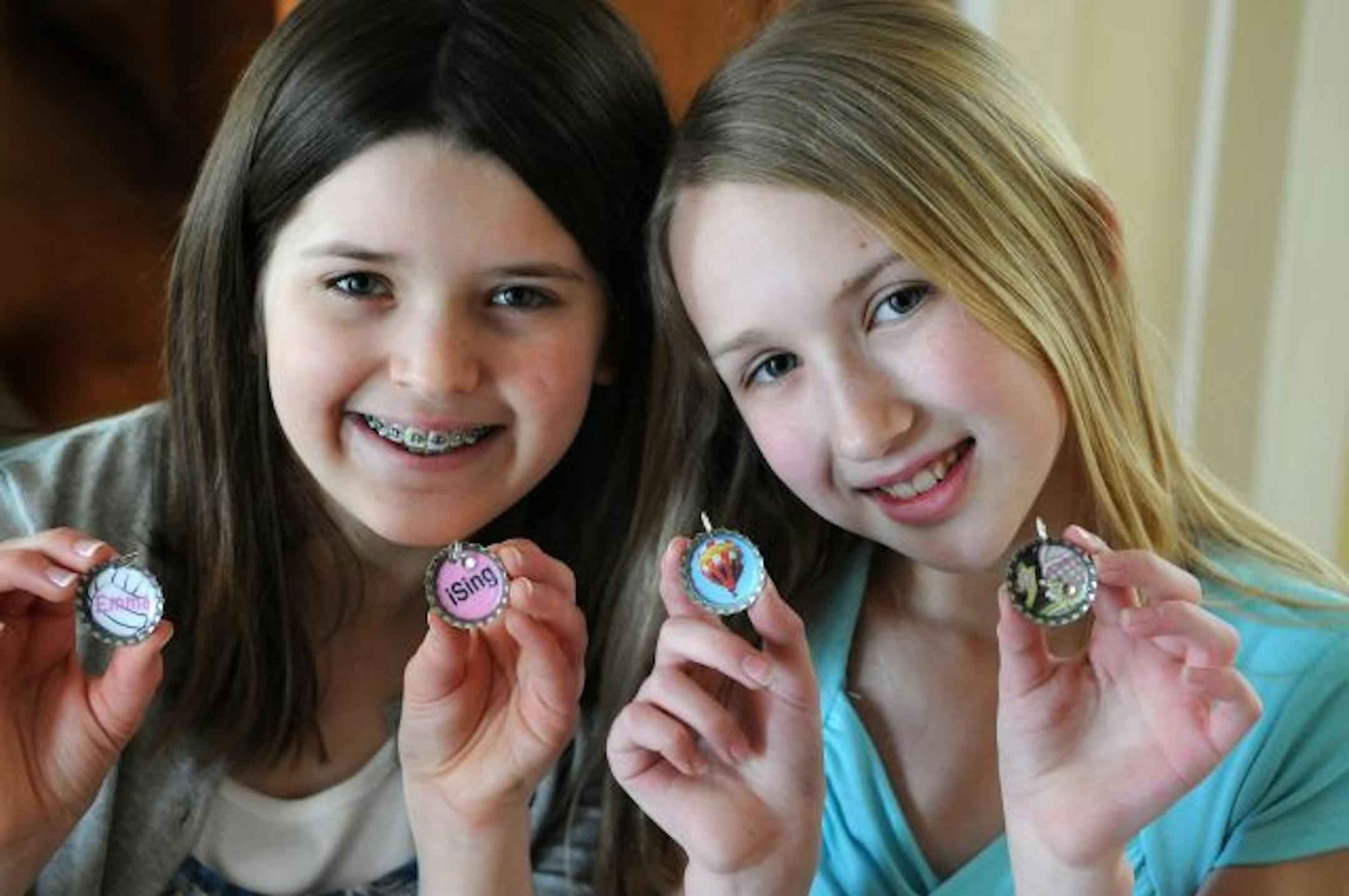 Emma Goos and Hannah Olson show off the bottle-cap charms that have become a huge hit at Dakota Hills Middle School. Now the girls are expanding their market.