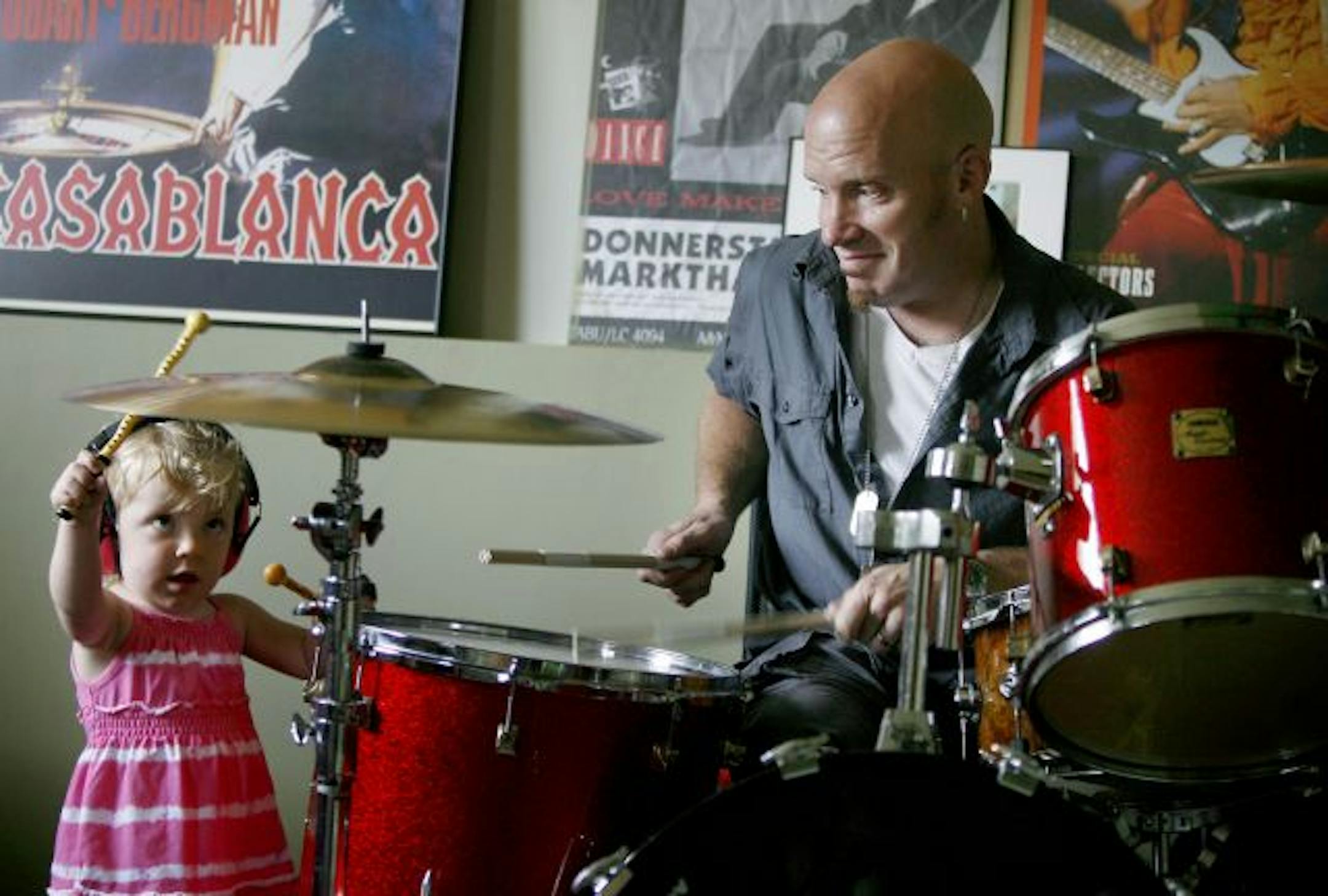 Ron Heyne's daughter, Grace, 2, wearing pink ear muffs, took to the drums with her father at their Eagan home.