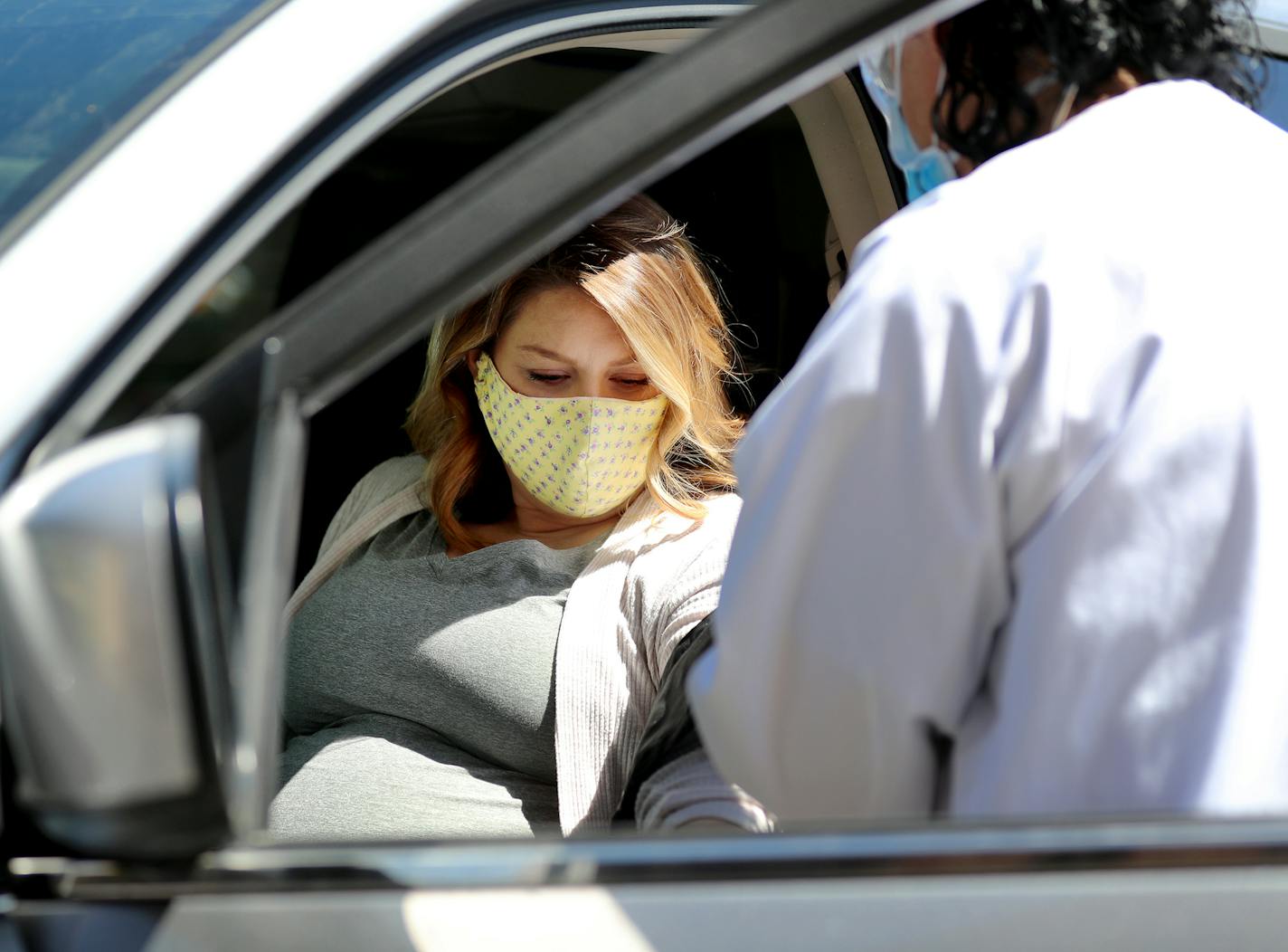 Kari Lutz, a medical assistant at M Health Fairview, right, checks the vitals of patient Katie Schugel during a curbside prenatal care visit Friday, May 15, 2020, in Burnsville.