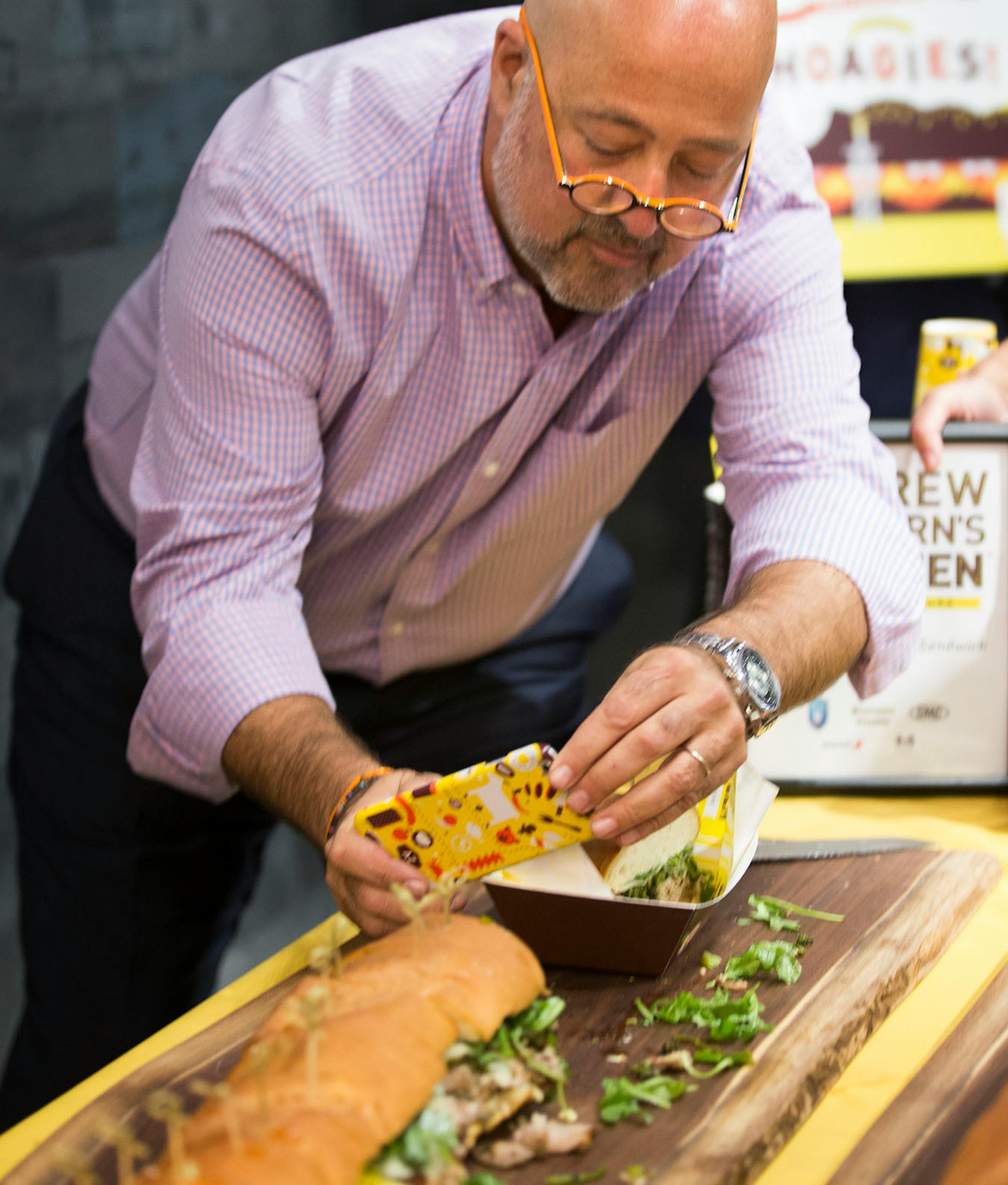 Andrew Zimmern takes a cell phone photo of a giant hoagie.