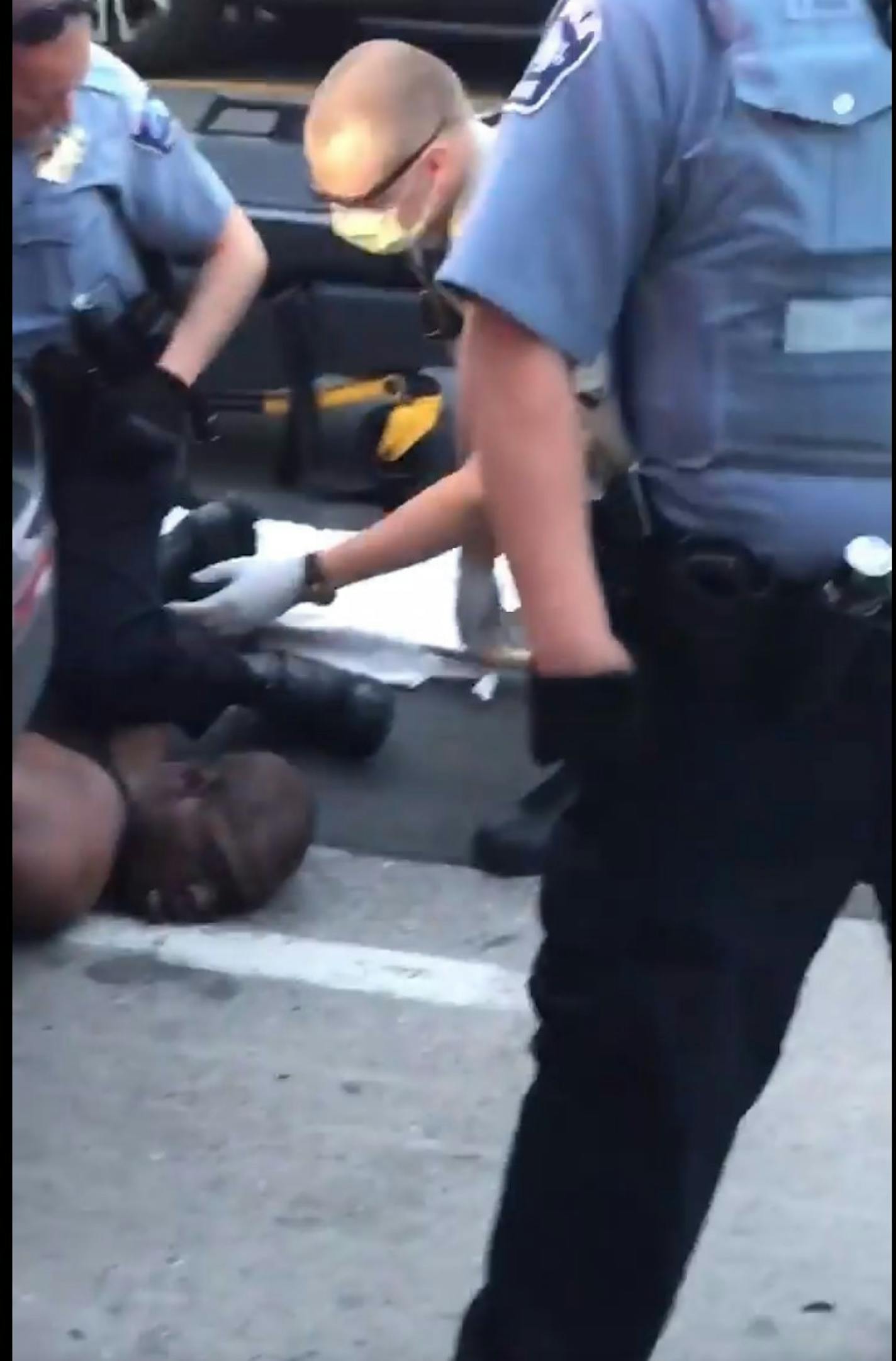 Officer Derek Chauvin's knee remains on an unresponsive George Floyd as a Hennepin County EMS worker prepares to load him onto a stretcher.