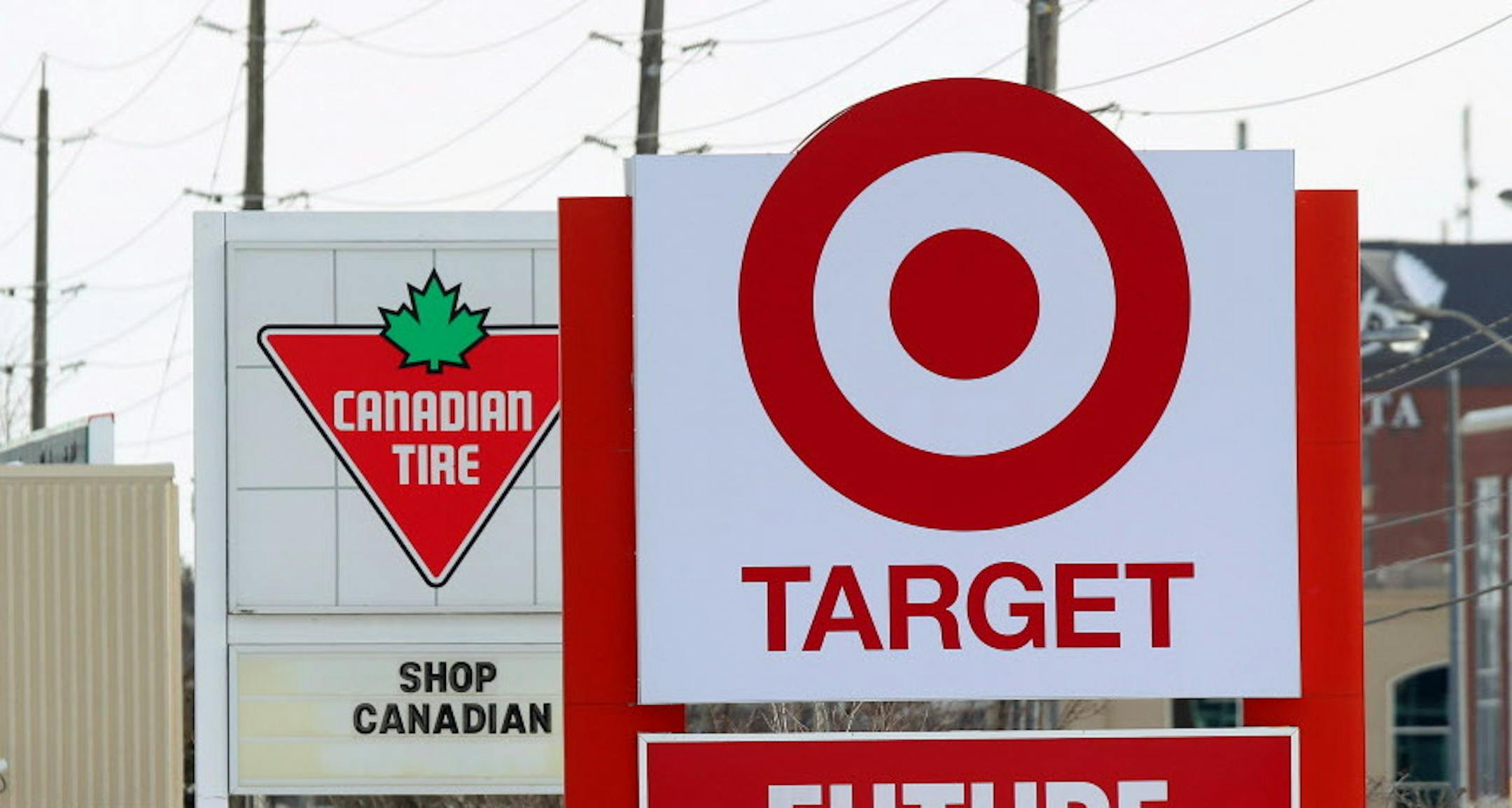 In this March 4, 2013 file photo, snow is piled in the parking lot of the new Target store in Guelph, Ontario as Canadian Tire posts a Canadian message on their sign. For years, Canadians would cross the border to the U.S. to shop at Target. Exporting its cheap chic there seemed like a no-brainer. But a year after opening more than 100 stores north of the border, Target has found business isnít so easy. Canadian Tire, which operates nearly 500 stores in the country and stocks housewares, ba