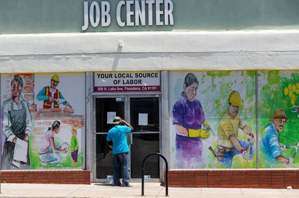 FILE - In this May 7, 2020, file photo, a person looks inside the closed doors of the Pasadena Community Job Center during the coronavirus outbreak in