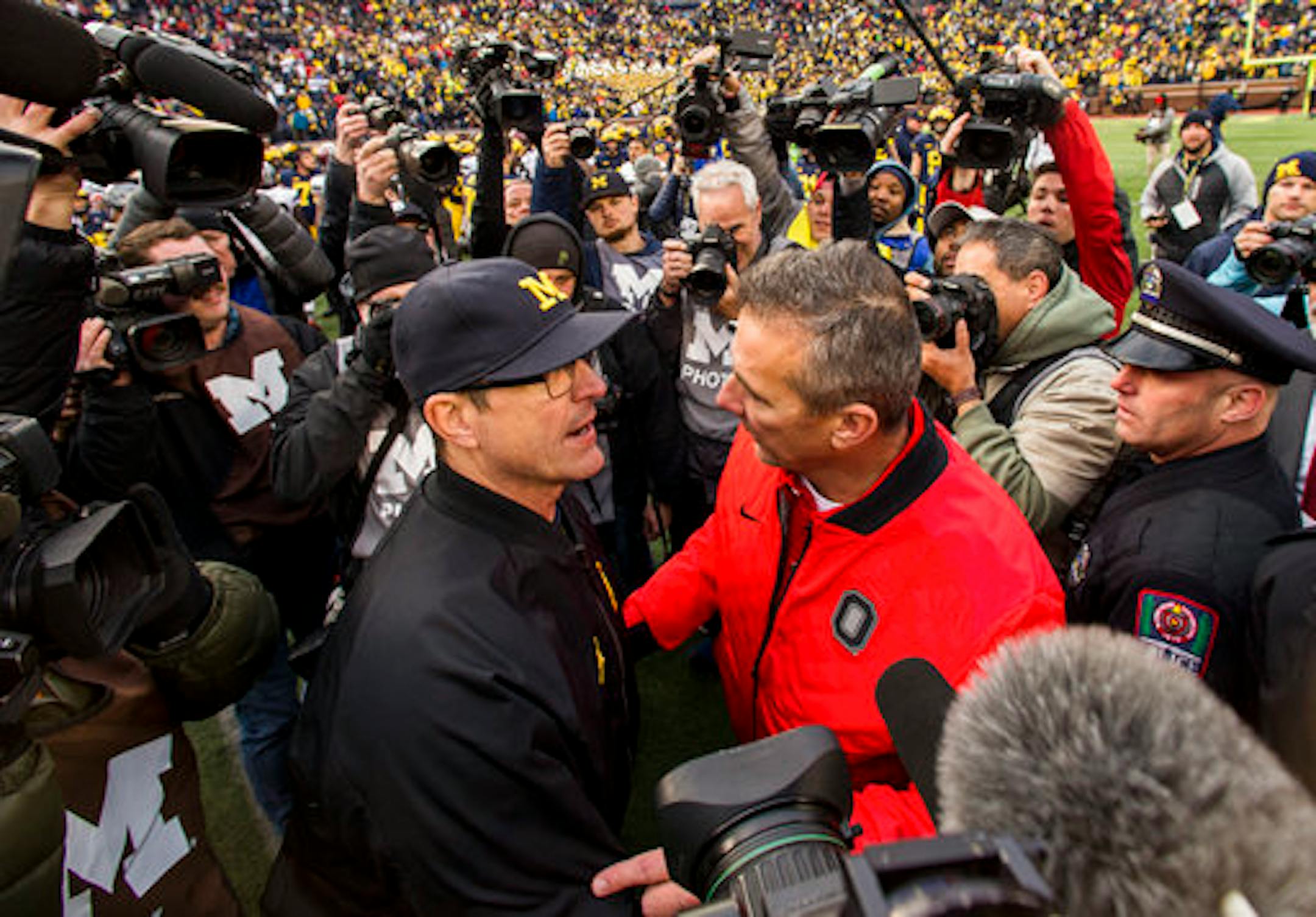 Michigan head coach Jim Harbaugh, center left, shakes hands with Ohio State head coach Urban Meyer, center right, after an NCAA college football game in Ann Arbor, Mich., Saturday, Nov. 25, 2017. Ohio State won 31-20. (AP Photo/Tony Ding)