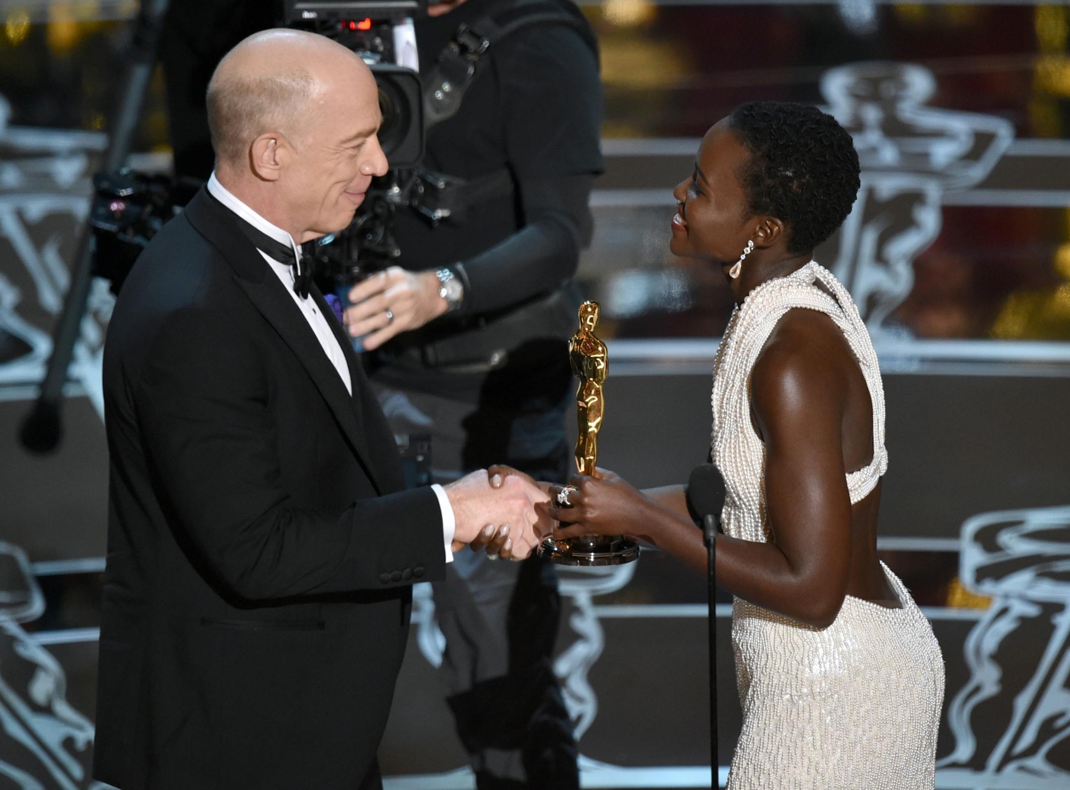 Lupita Nyong'o, right, presents J.K. Simmons with the award for best actor in a supporting role for �Whiplash� at the Oscars on Sunday, Feb. 22, 2015, at the Dolby Theatre in Los Angeles.