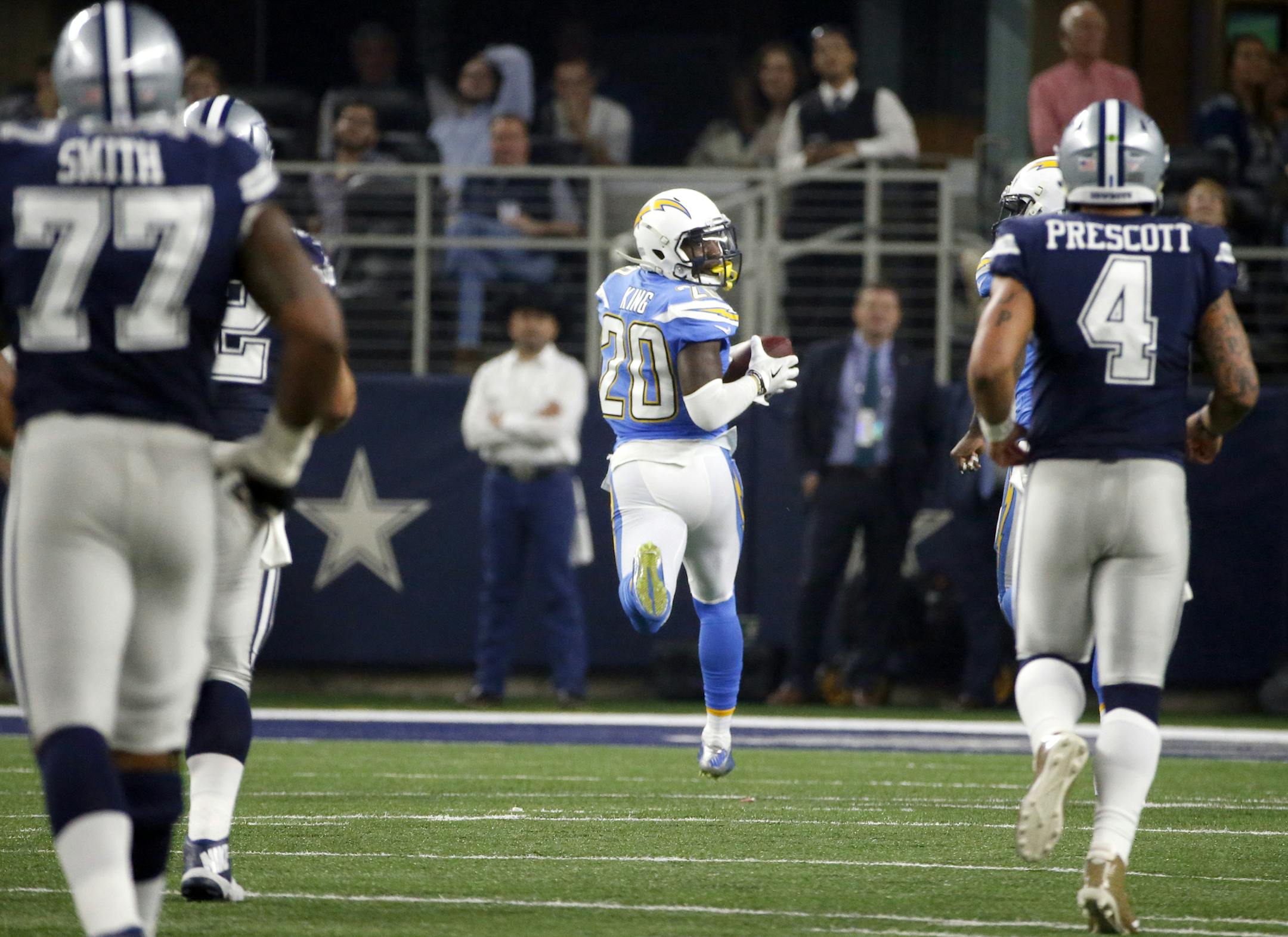 Dallas Cowboys' Tyron Smith (77) and quarterback Dak Prescott (4) watch as Los Angeles Chargers cornerback Desmond King (20) returns an interception for a touchdown in the second half of an NFL football game, Thursday, Nov. 23, 2017, in Arlington, Texas. (AP Photo/Michael Ainsworth)