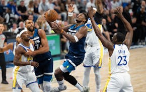 Timberwolves guard Anthony Edwards (5) goes up for a layup while being defended by Golden State Warriors guard Gary Payton II (0) and forward Draymond