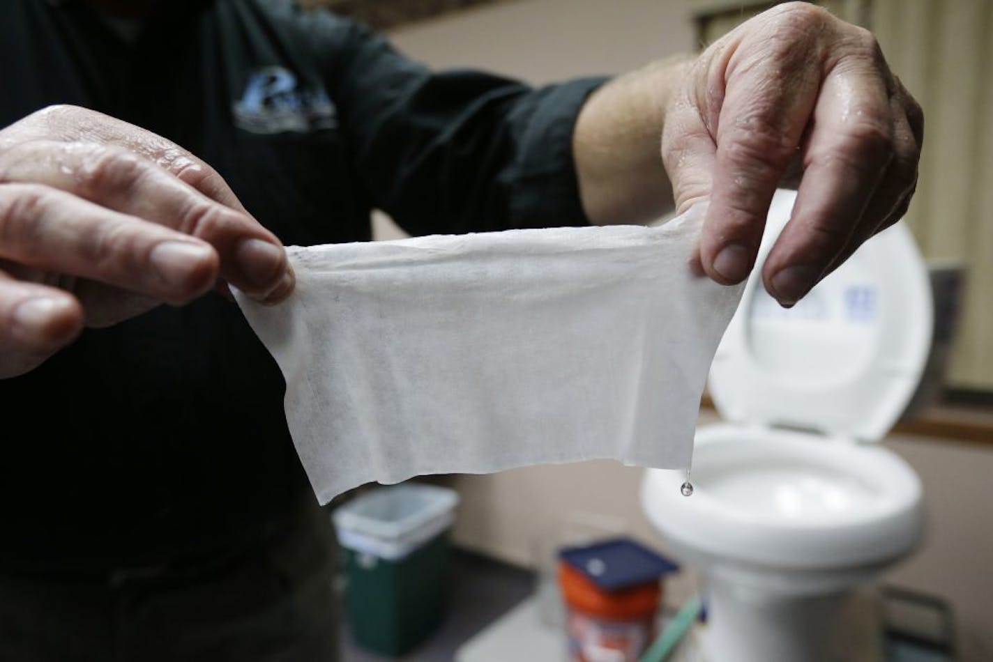 In this photograph taken, Friday, Sept. 20, 2013, in Middlesex, N.J., Rob Villee, executive director of the Plainfield Area Regional Sewer Authority in New Jersey, holds up a wipe he flushed through his test toilet in his office. Increasingly popular bathroom wipes, thick, premoistened towelettes that are advertised as flushable, are creating clogs and backups in sewer systems around the nation. The problem has gotten so bad in this upstate New York town that frustrated sewer officials traced th