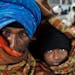An elderly Indian man shares a blanket with his son as they wait at a railway station on a cold morning in Allahabad, India, Friday, Jan. 10, 2014. Fo