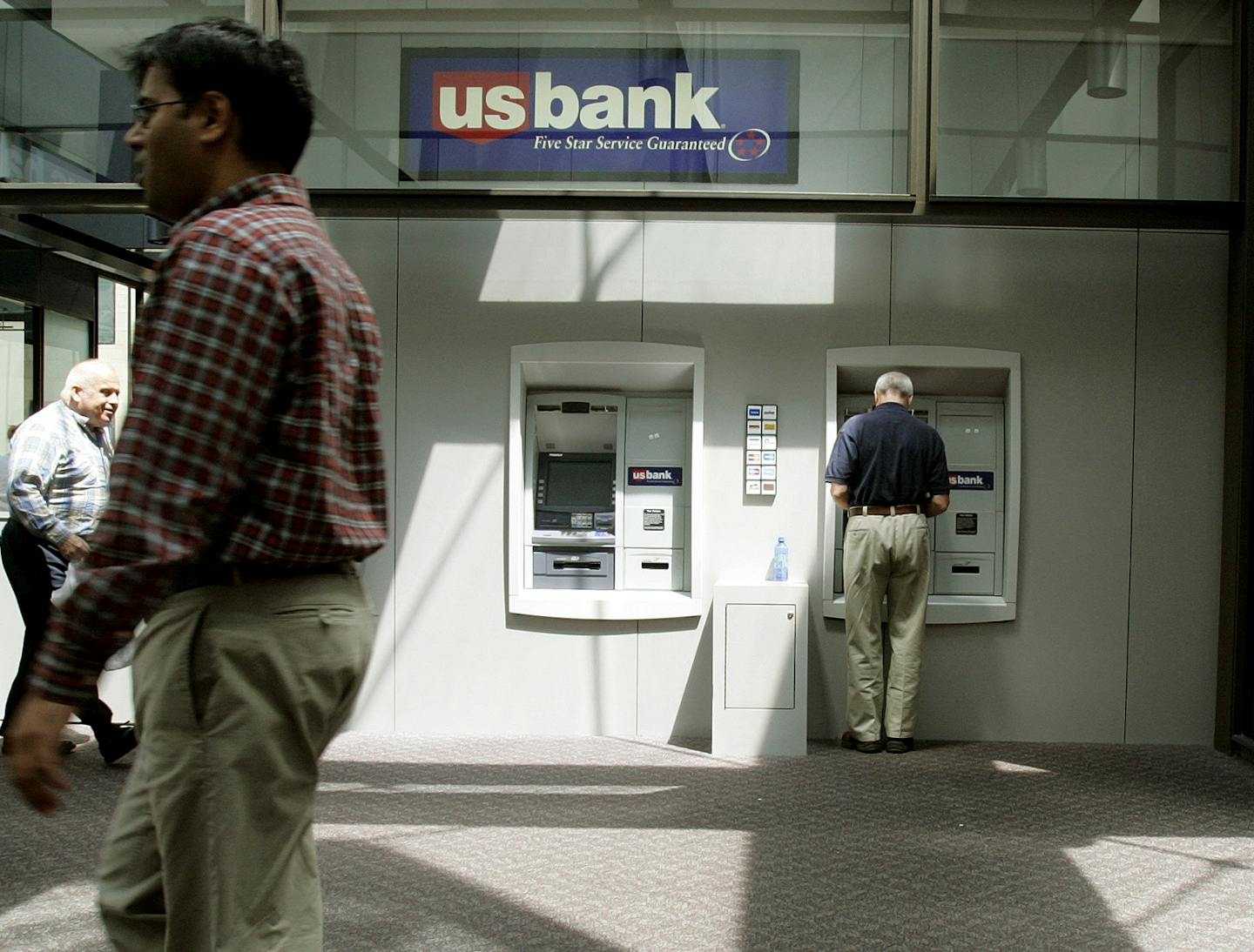 In this July 18, 2008 file photo. a customer uses a U.S. Bank ATM in a Minneapolis. U.S. Bancorp said Tuesday, Oct. 21, 2008, its third-quarter profit fell 47 percent, below analysts' expectations, as it took hits on investments and set aside a bigger provision for credit losses.