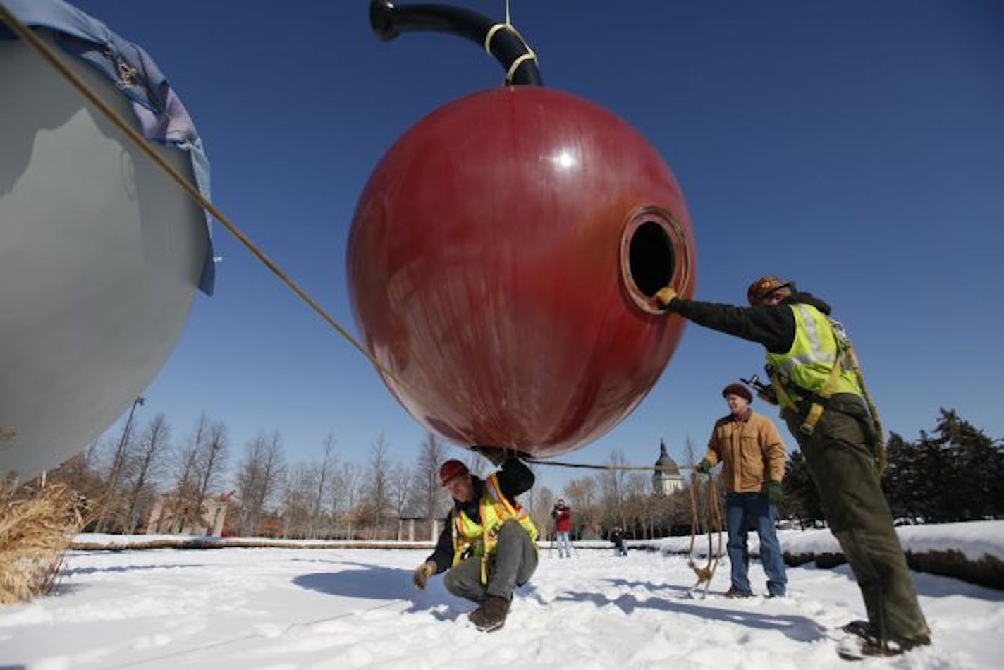 (Left to Right) At the Minneapolis Sculpture Garden, Leon Budke, an oilman for Rocket Crane crawled out of the 1,200 lbs. cherry from Spoonbridge and Cherry by Claes Oldenburg and Coosje van Bruggen. The cherry is destined for repainting and renovation but should be back on the spoon in the spring.