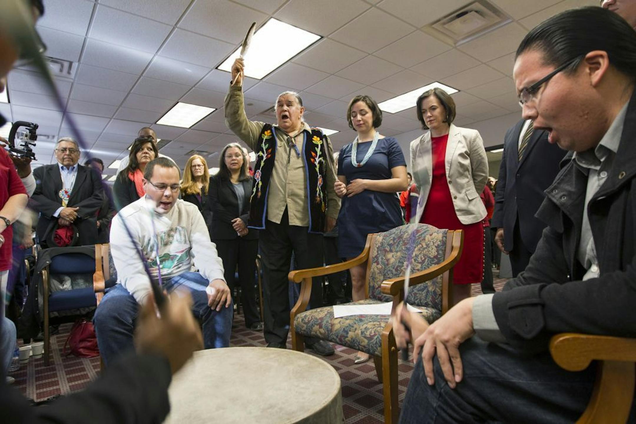 Thunder Before the Storm (Clyde Bellecourt) holds up a condor feather after leading a prayer as the Ringing Shield Drum circle sings before the Minneapolis City Council unanimously voted to call what has been known as Columbus Day "Indigenous People's Day" on April 25, 2014.