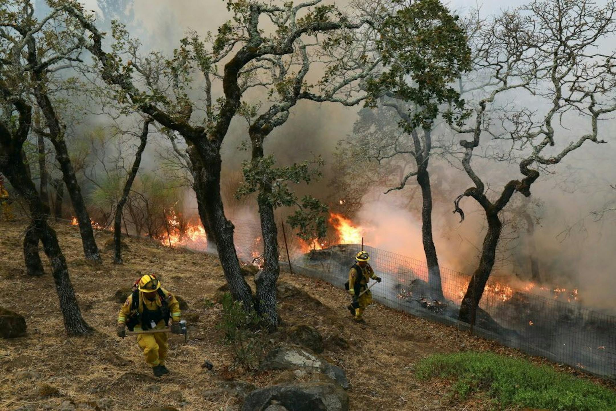 Firefighters monitor a backfire they set in Sonoma, Calif., on Wednesday, Oct. 11, 2017. On the front lines, exhausted crews battling raging wildfires are stretched to their limits, with blazes �burning faster than firefighters can run.�