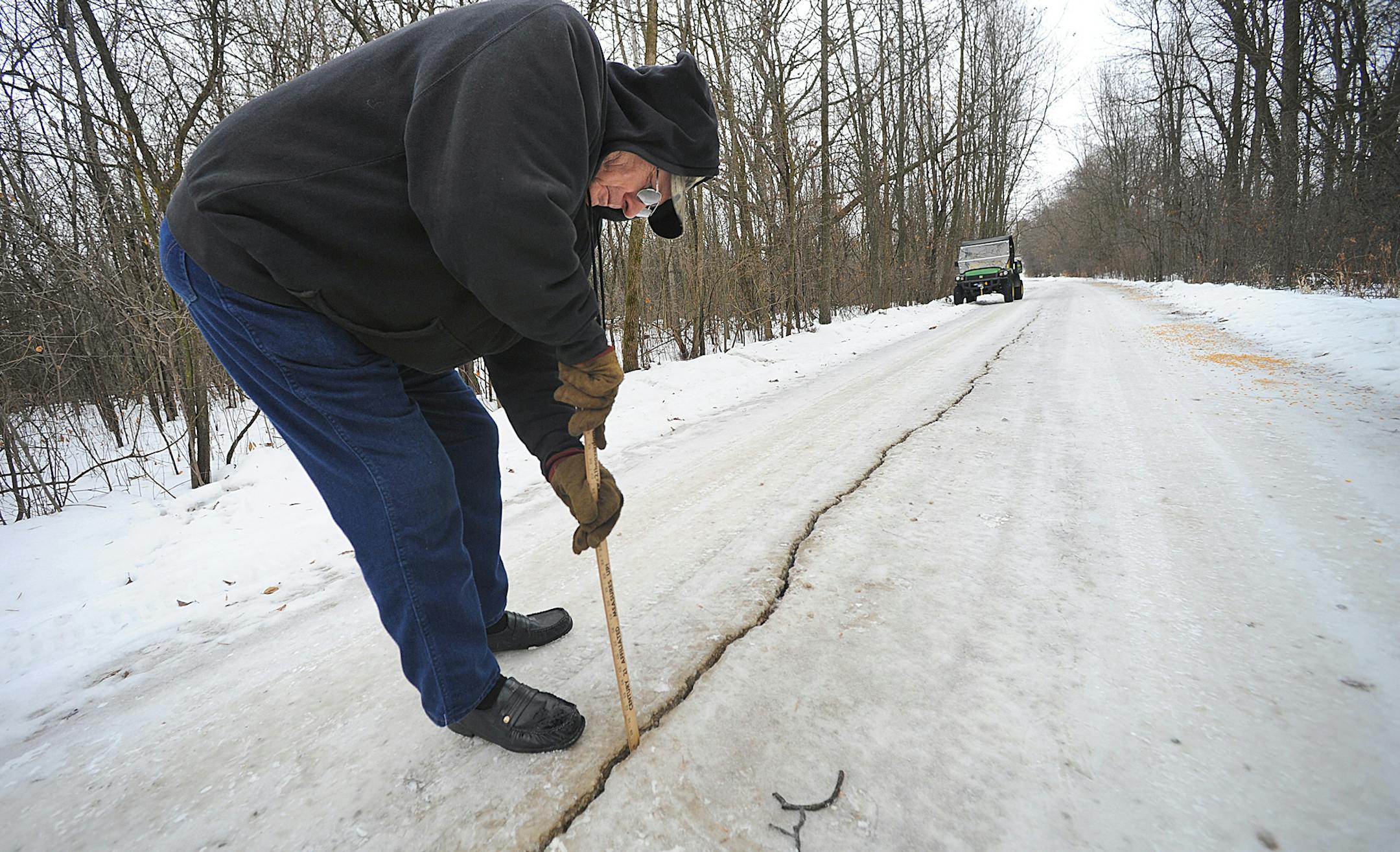 Jan. 11, 2014: Dennis Olsen measures a fissure which he said was about an inch wide and at least 8 to 10 inches deep, in his rural driveway following a frost quake in Waupun, Wis.
