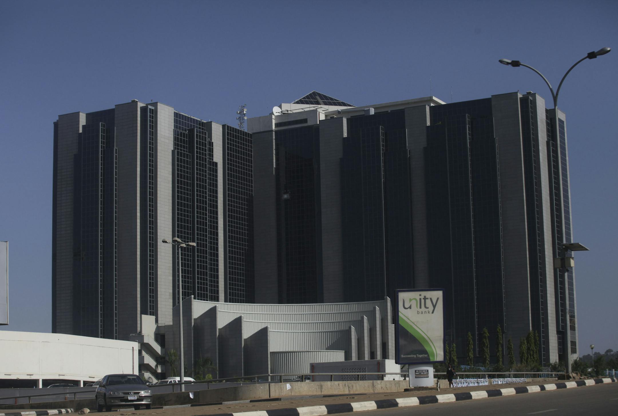 In this photo taken Friday, Nov. 11, 2011, A man stand in front of a Central bank of Nigeria a modern style of architectural design in Abuja, Nigeria. What will one day be the most populous city in Africa was initially ignored by the Portuguese explorers who first dominated it, served as a hub for a brutal slave trade and once held the hope of a continent that even now struggles to overcome its colonial past.(AP Photos/Sunday Alamba) ORG XMIT: NIN134