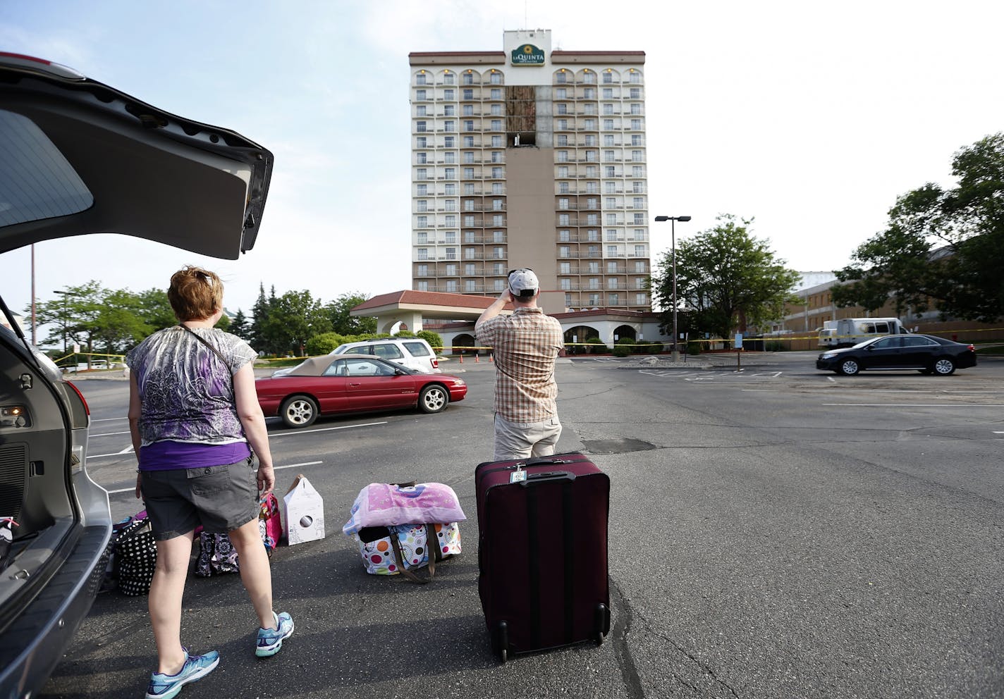 Jay Schlenker took a photo as he and his wife Linda were loading up their car in the parking lot of the La Quinta Inn & Suites in Bloomington. The hotel had its facade panels on the 14th-17th floors fall early Monday morning.